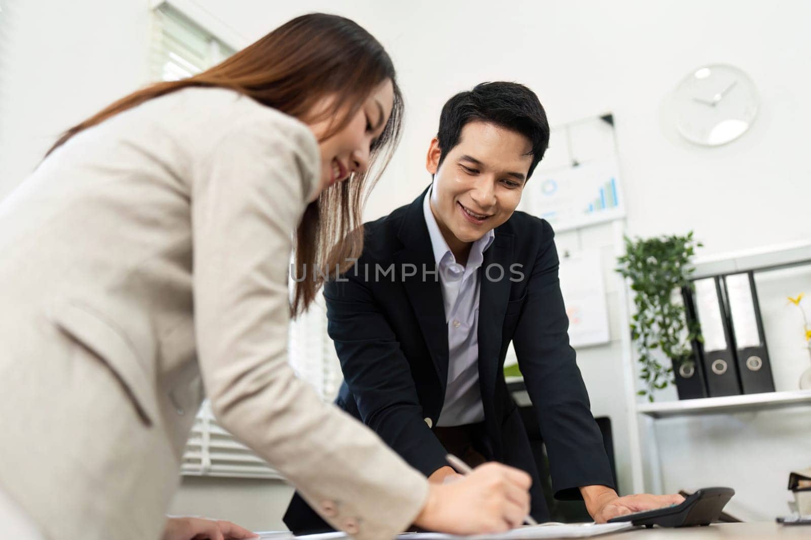 A man and woman collaborating on financial documents, showcasing teamwork and strategic planning in a modern workspace.