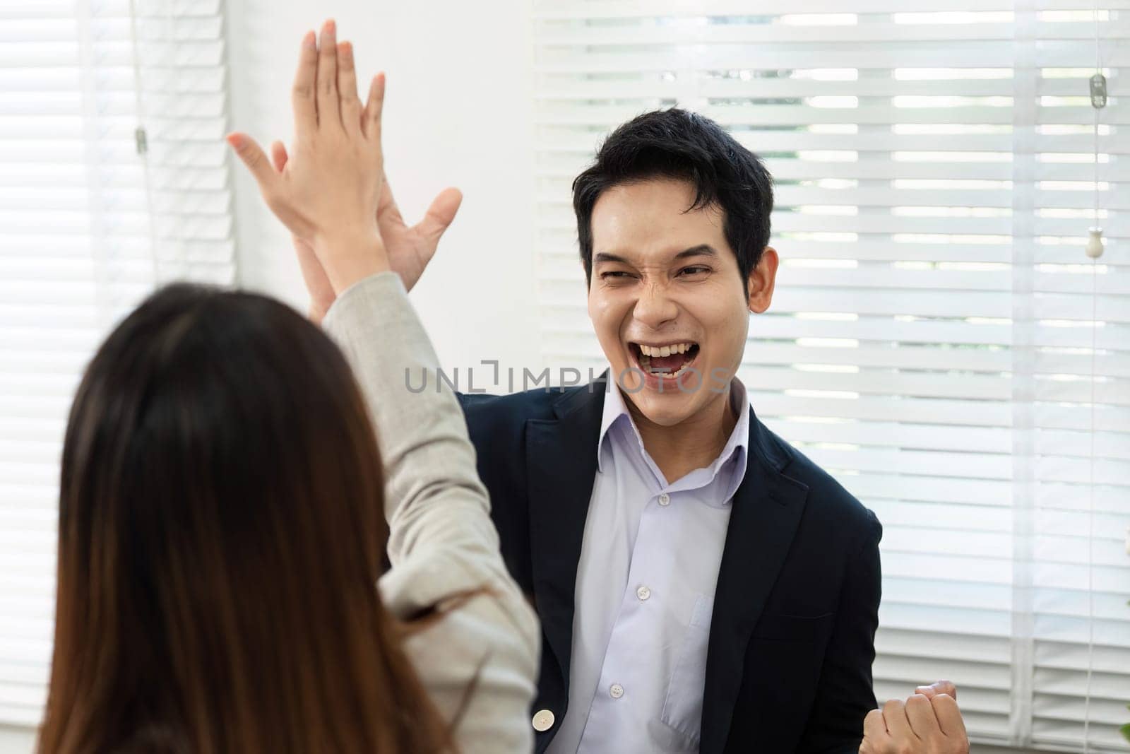 A joyful moment as colleagues celebrate a successful project completion with high-fives in a bright office environment.