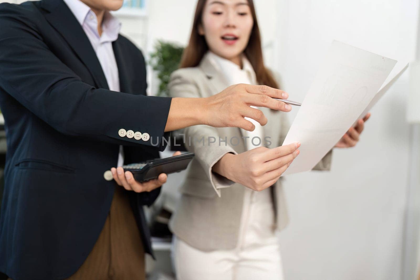 Two business professionals engaged in a strategic discussion, reviewing project documents and collaborating in a bright office environment.