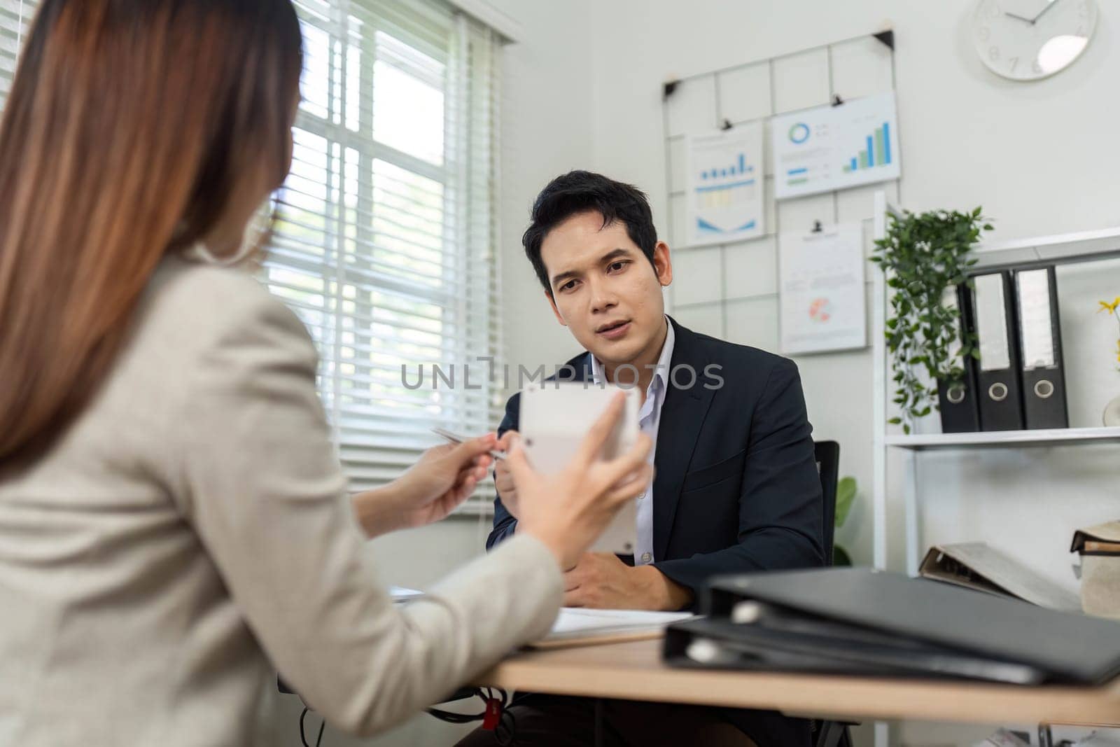 A focused business meeting where a man and woman discuss financial strategies and share insights in a modern office setting.