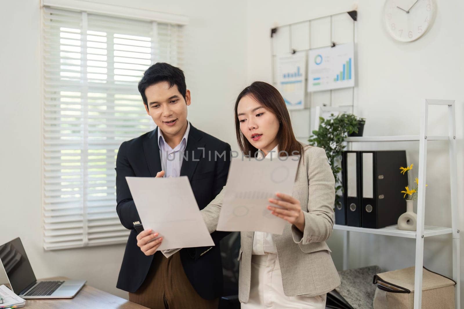 Two business professionals engage in a strategic discussion, reviewing project documents and collaborating in a contemporary office environment.