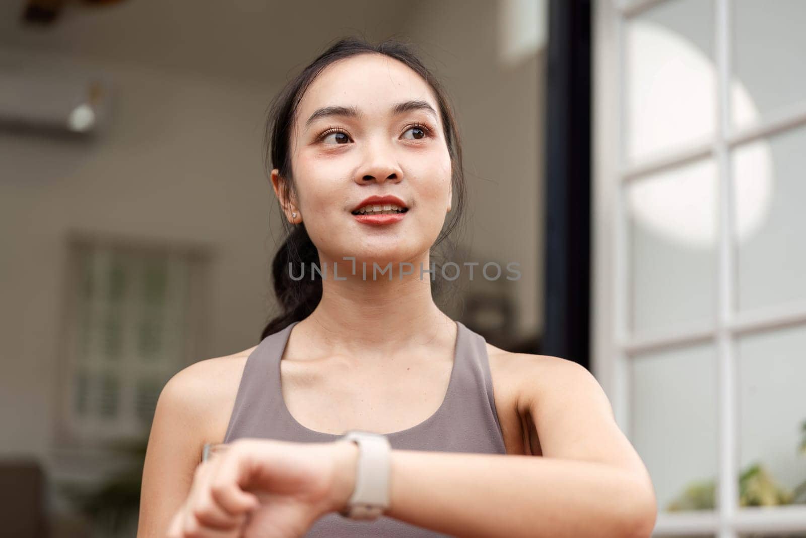 A fitness-focused woman checks her smartwatch, smiling and enjoying her workout experience, promoting positivity and health.
