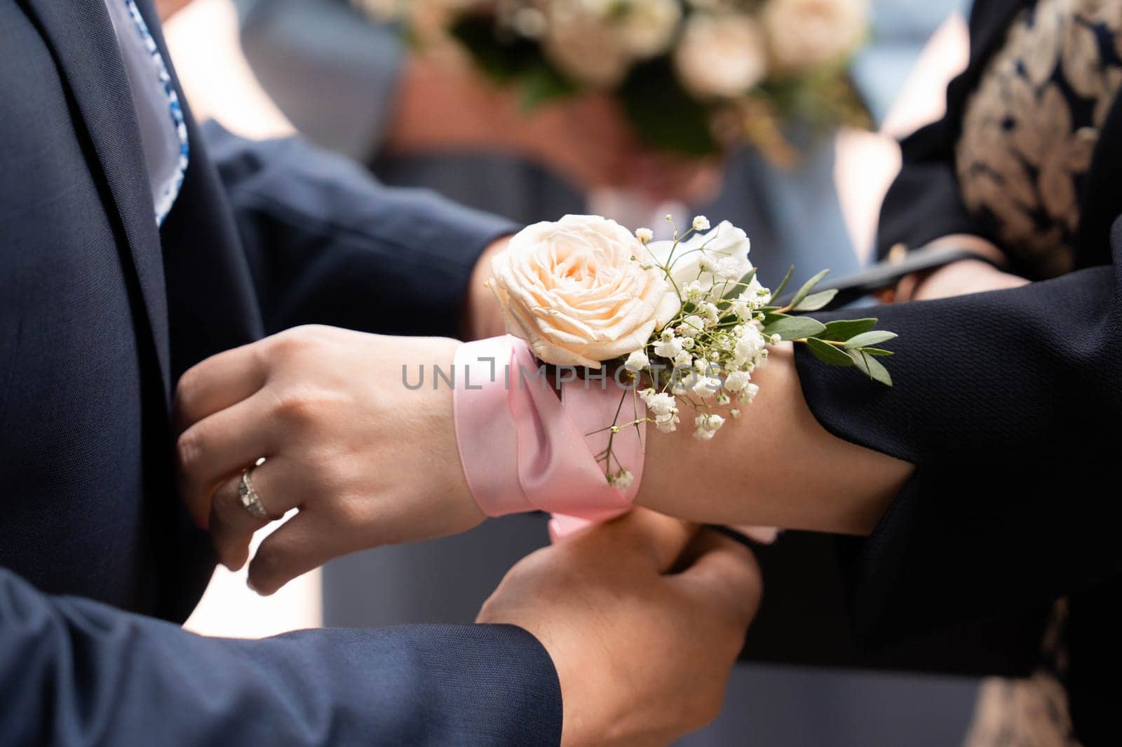 The bridesmaid gets a bracelet made of a pink ribbon and roses tied on her hand