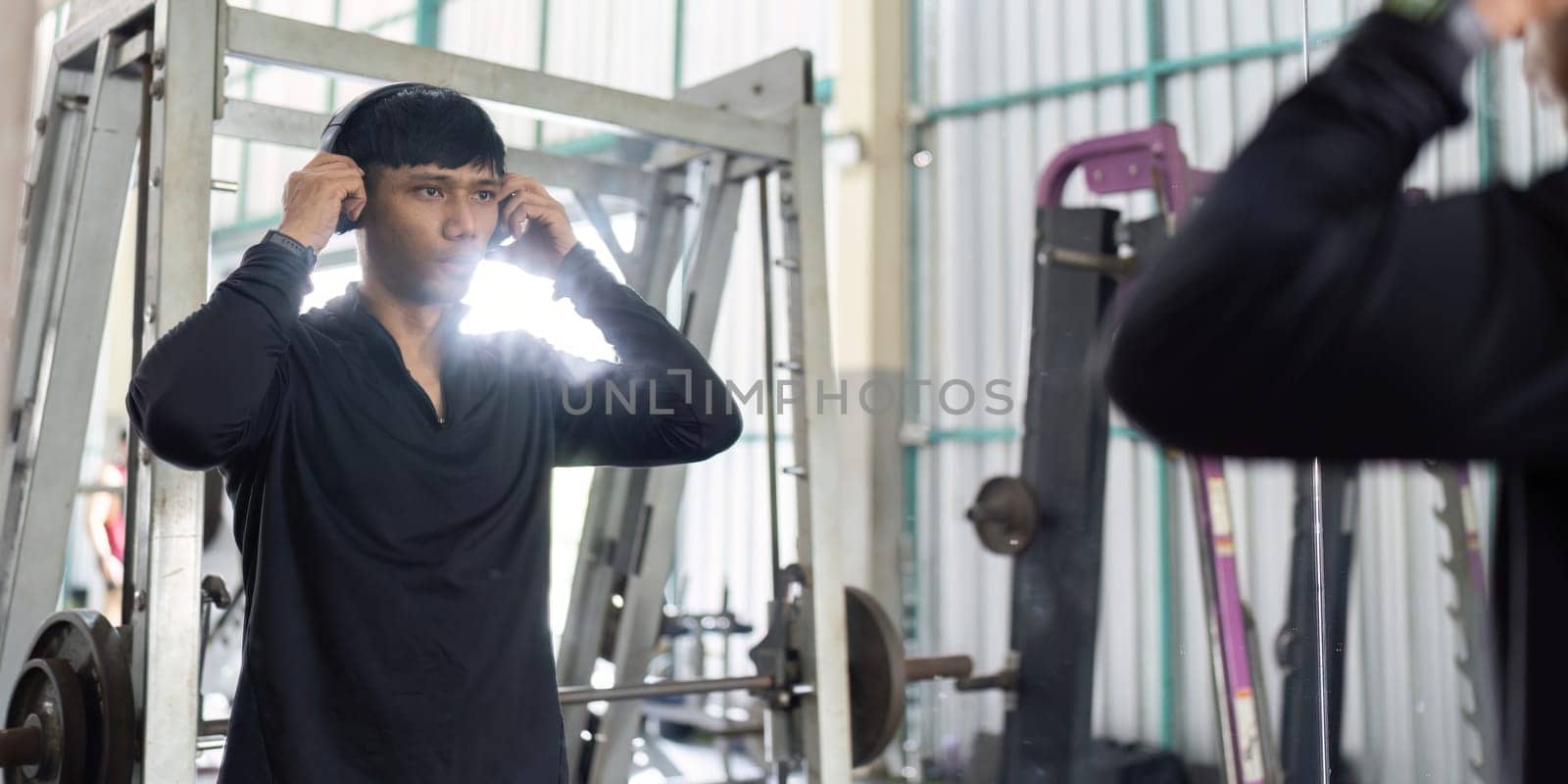 A focused man prepares for his workout by adjusting his headphones, ready to engage in fitness training.