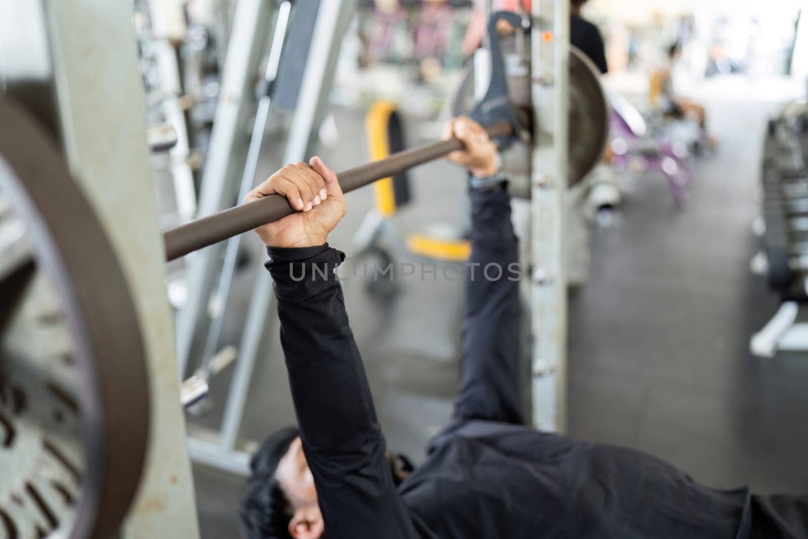 A determined man performs a bench press exercise, showcasing strength training and fitness commitment in the gym.