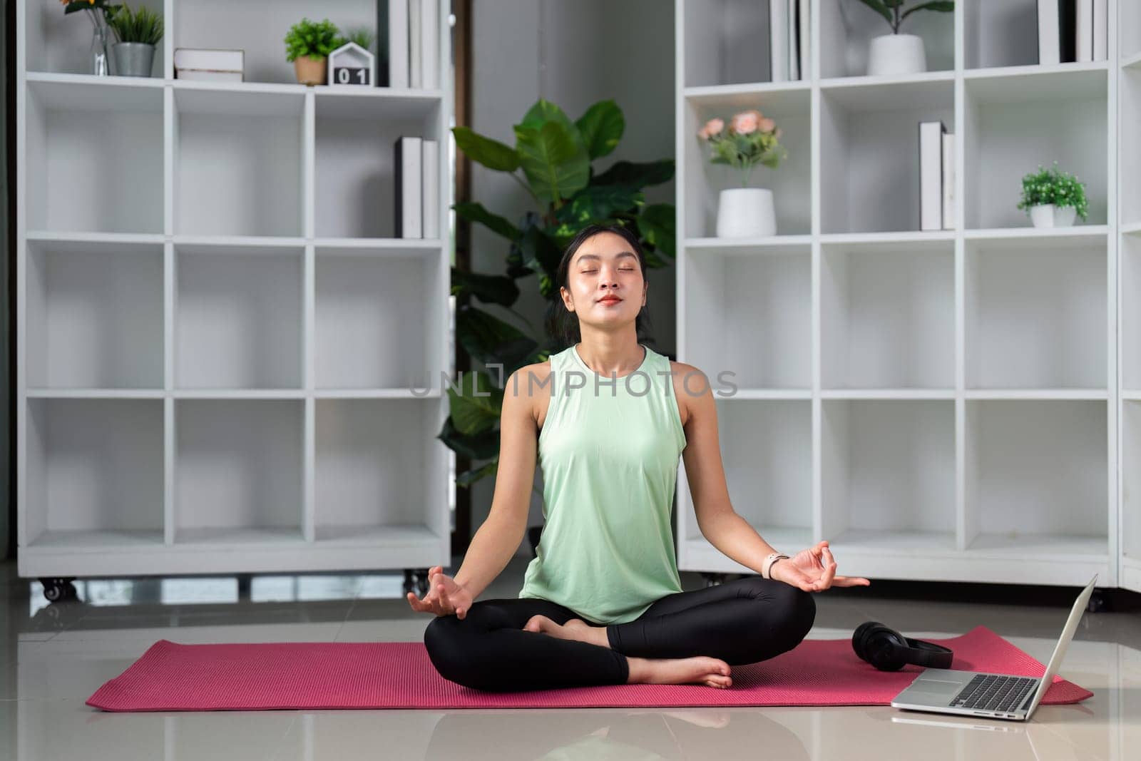 In a peaceful yoga space, a woman practices meditation, surrounded by calm, showcasing her journey towards mindfulness and stress relief through deep focus and breathing.