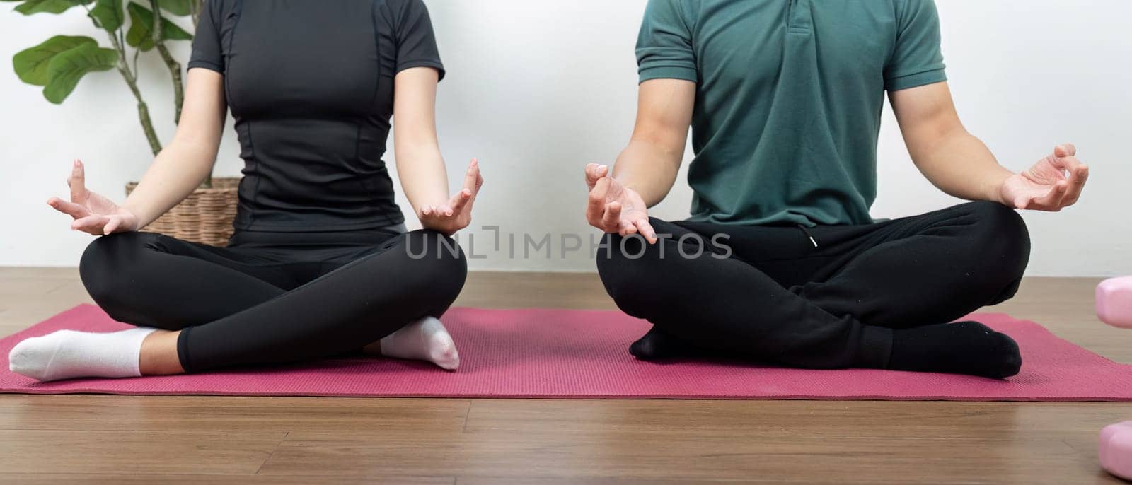 A couple in a meditative pose, promoting wellness and mindfulness in a serene indoor environment.