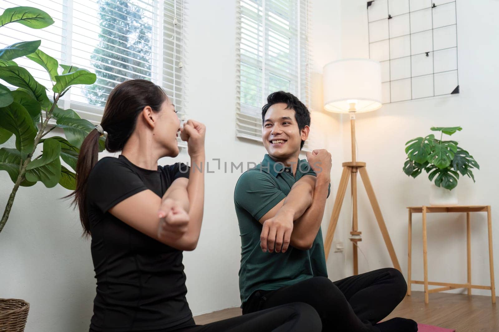A couple practicing wellness stretches together in a cozy indoor setting, promoting health and connection.