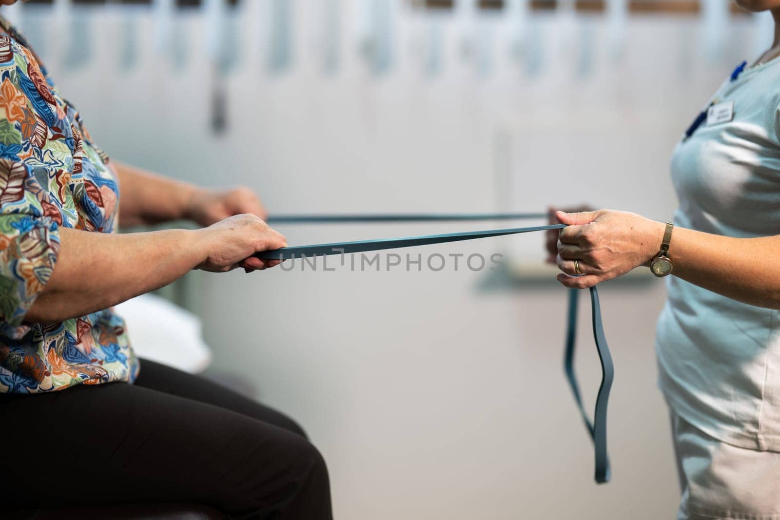 Senior woman doing physical exercises with the help of a smiling therapist. Concept of elderly rehabilitation and movement recovery.