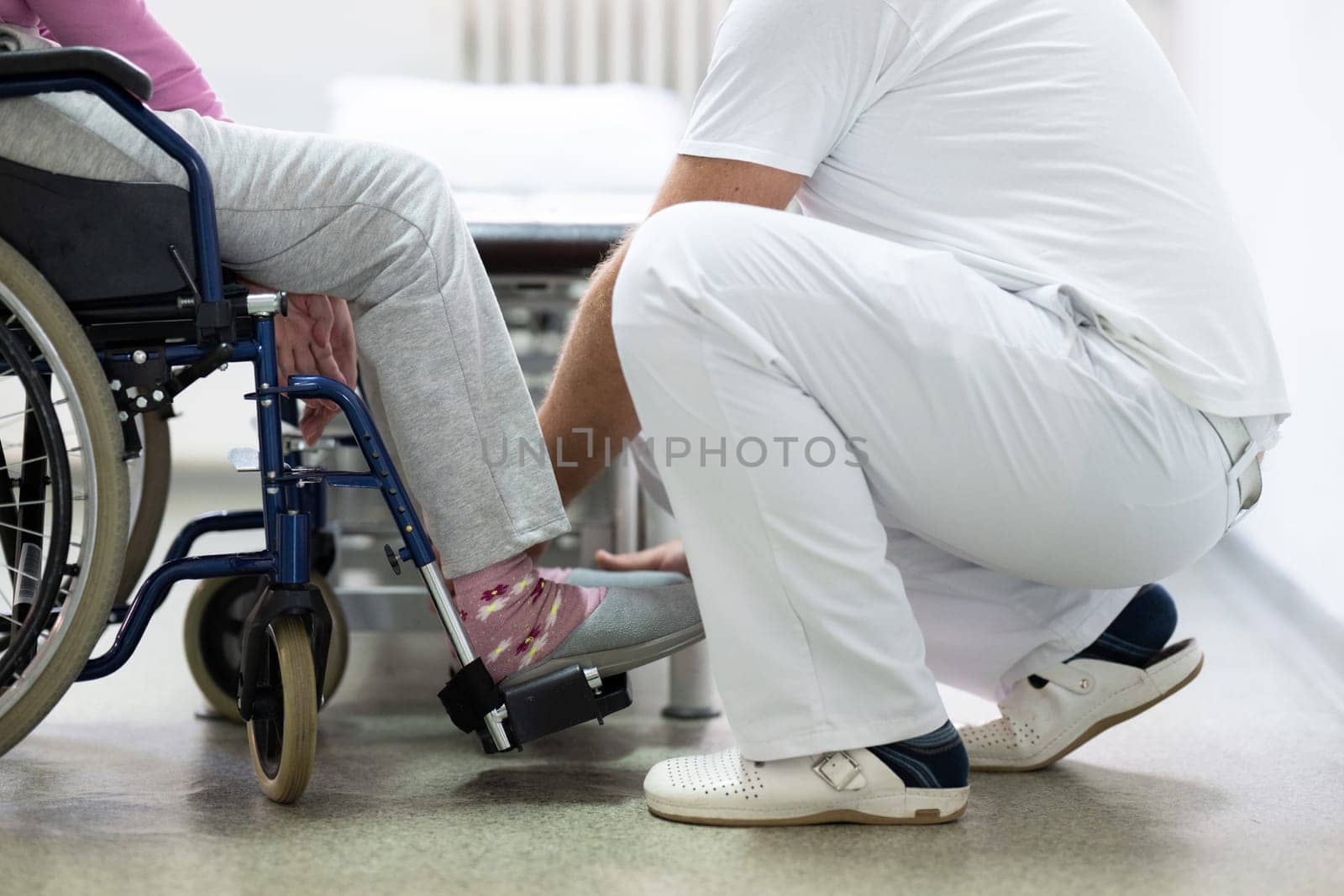 Senior woman doing physical exercises with the help of a smiling therapist. Concept of elderly rehabilitation and movement recovery.