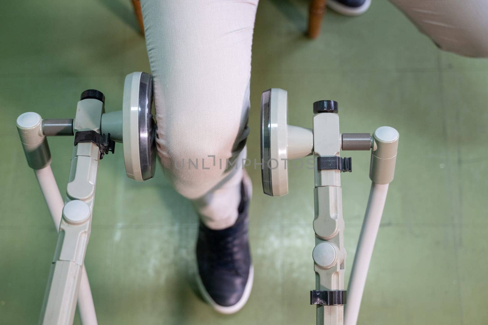 Top down view of a person using a rehabilitation machine for leg therapy, focusing on muscle training and mobility.