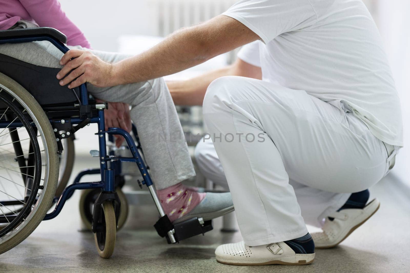 Senior woman doing physical exercises with the help of a smiling therapist. Concept of elderly rehabilitation and movement recovery.