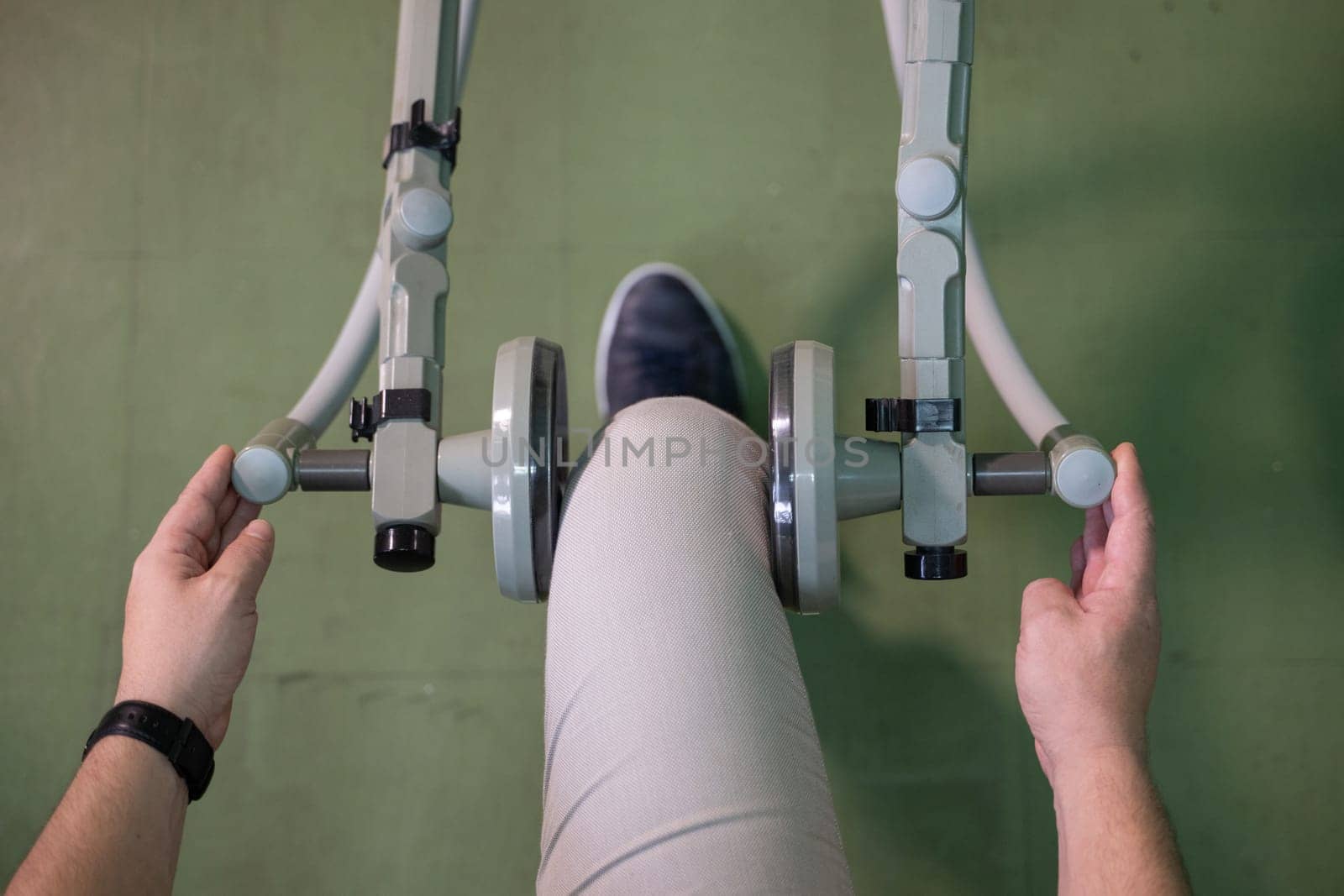 Top down view of a person using a rehabilitation machine for leg therapy, focusing on muscle training and mobility.