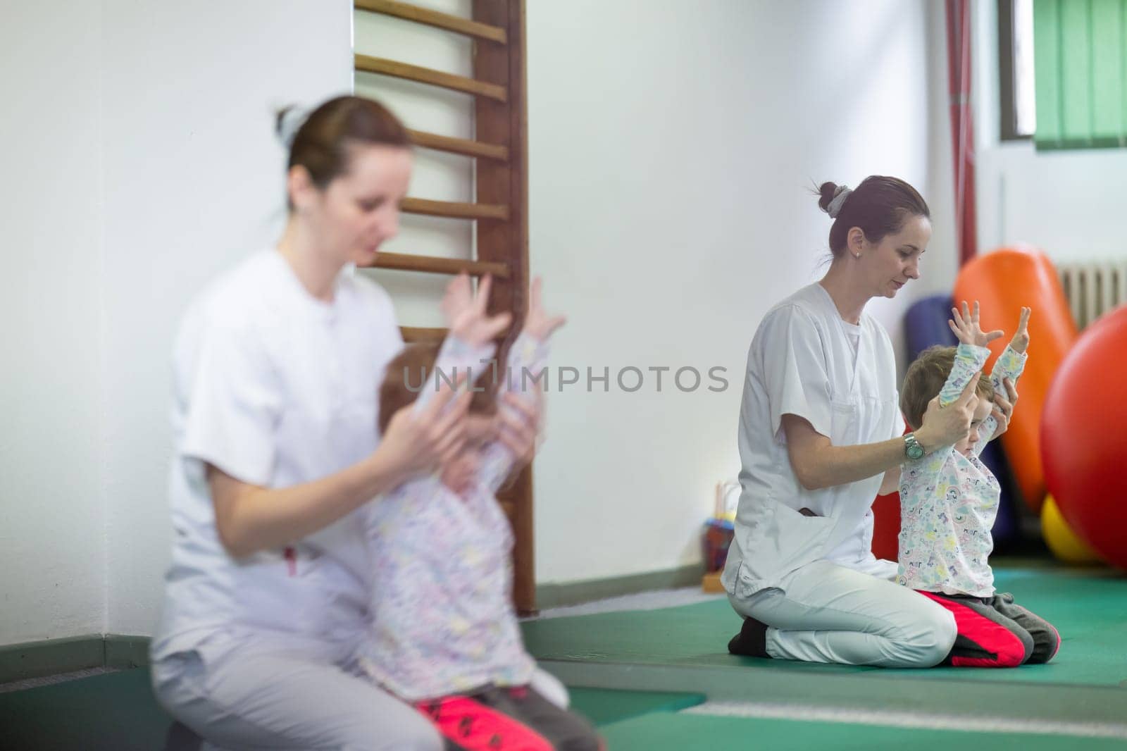 Female physiotherapist helping a young child with physical exercises in a rehabilitation center. Pediatric therapy and development concept.