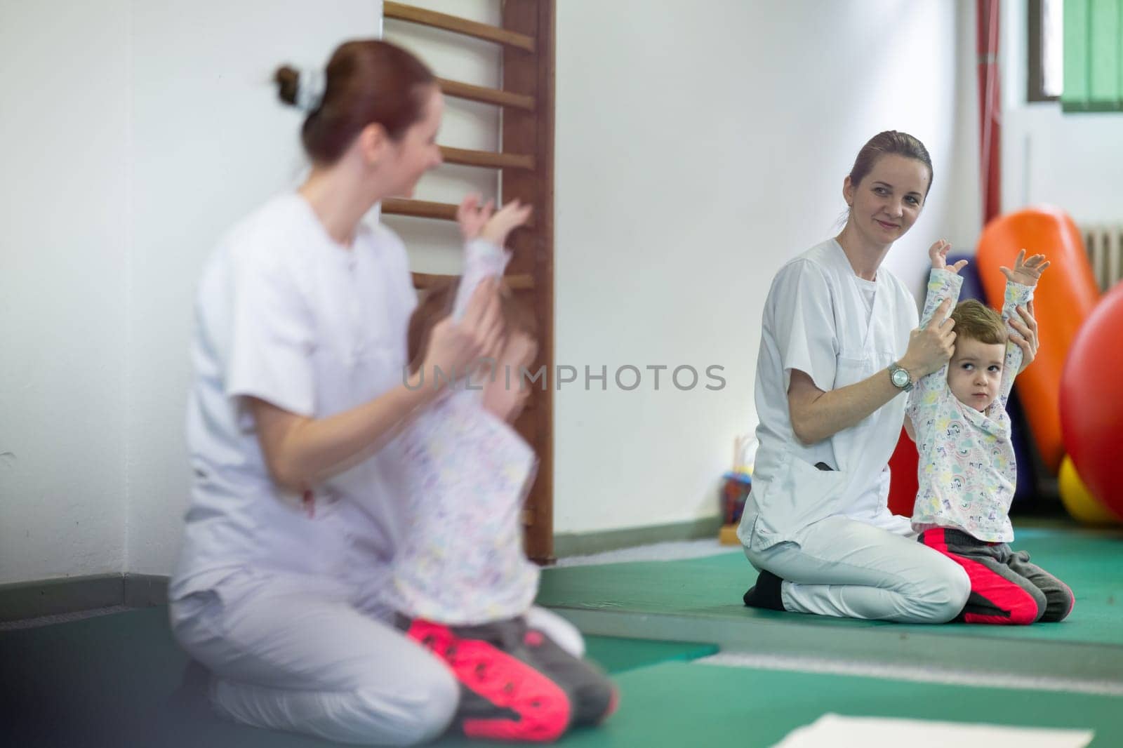Female physiotherapist helping a young child with physical exercises in a rehabilitation center. Pediatric therapy and development concept.