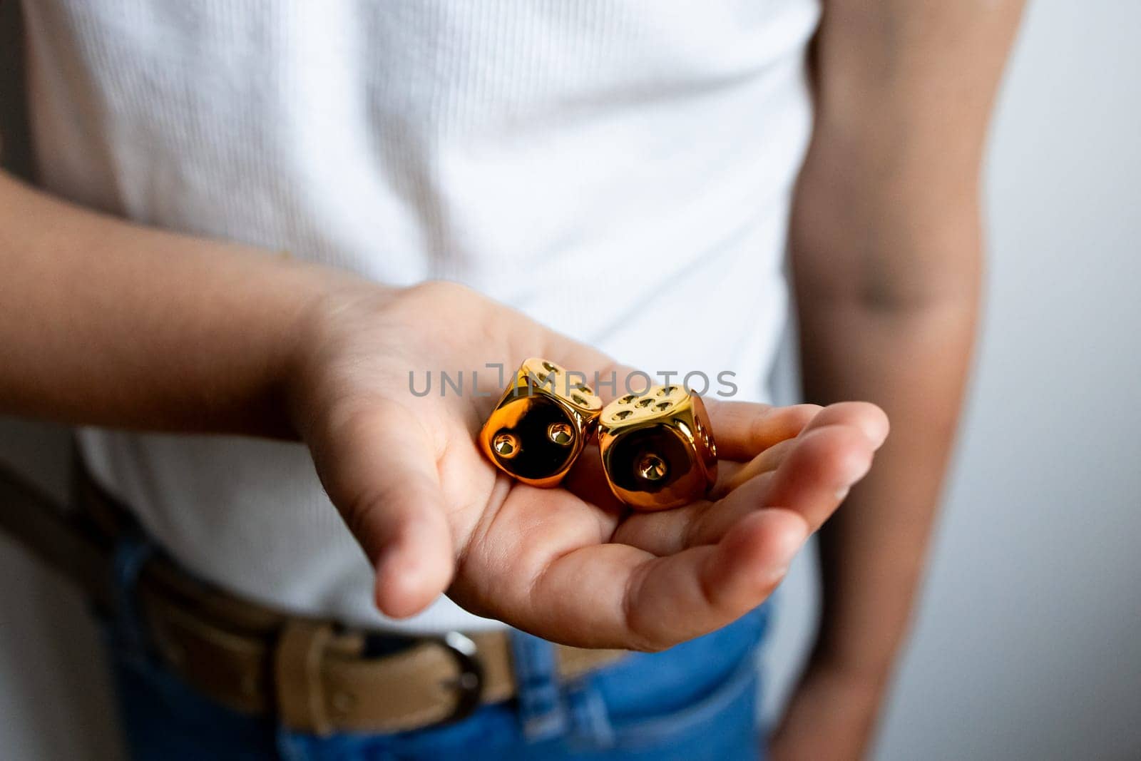 Young hispanic female holding golden dice in hand.