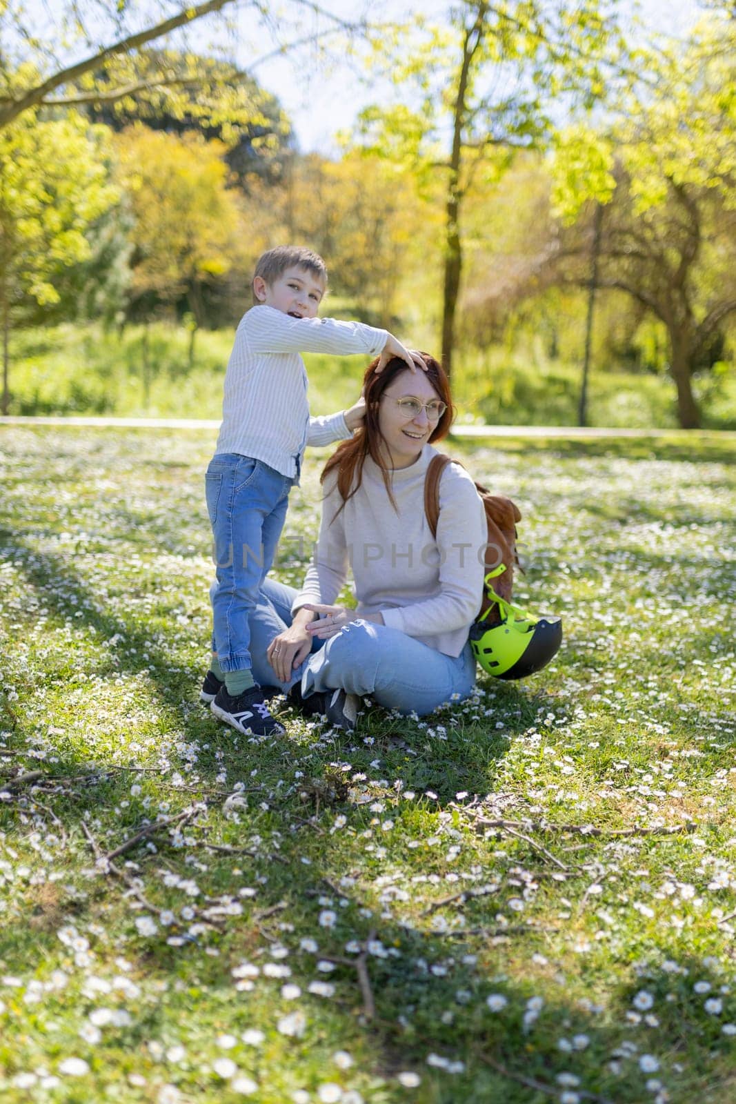 Happy mother and child enjoying a sunny spring day in a park, surrounded by daisies