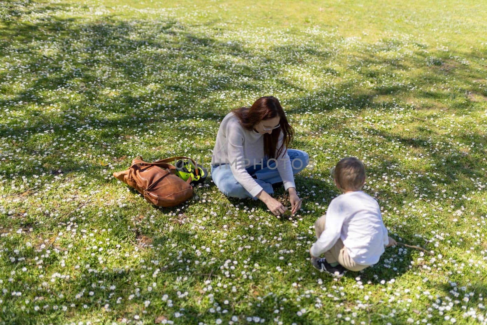 Mother and son enjoying a sunny spring day picking daisies in a field of flowers