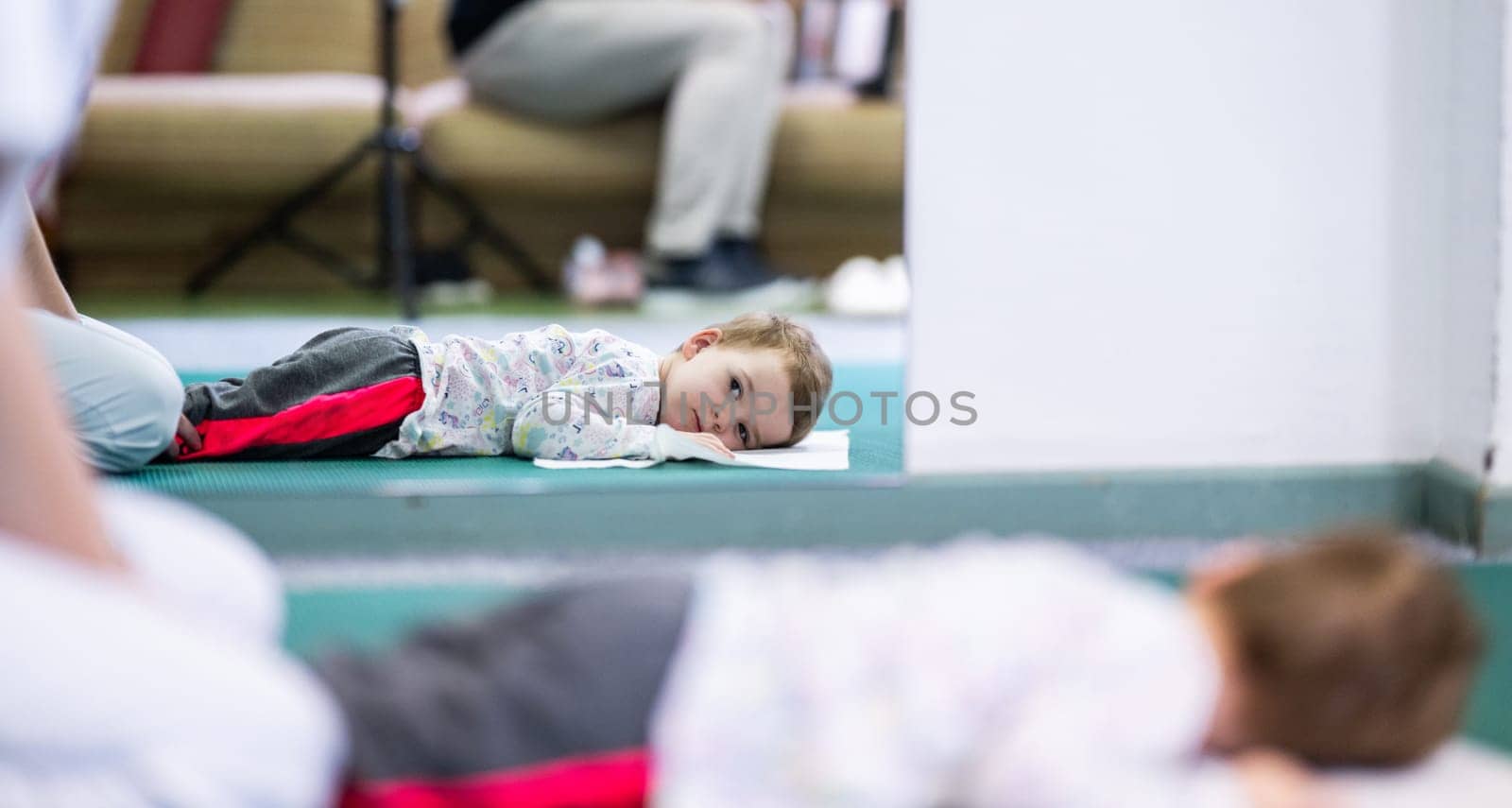 Young boy on a therapy mat during a physiotherapy session, engaging in a supervised stretching activity.