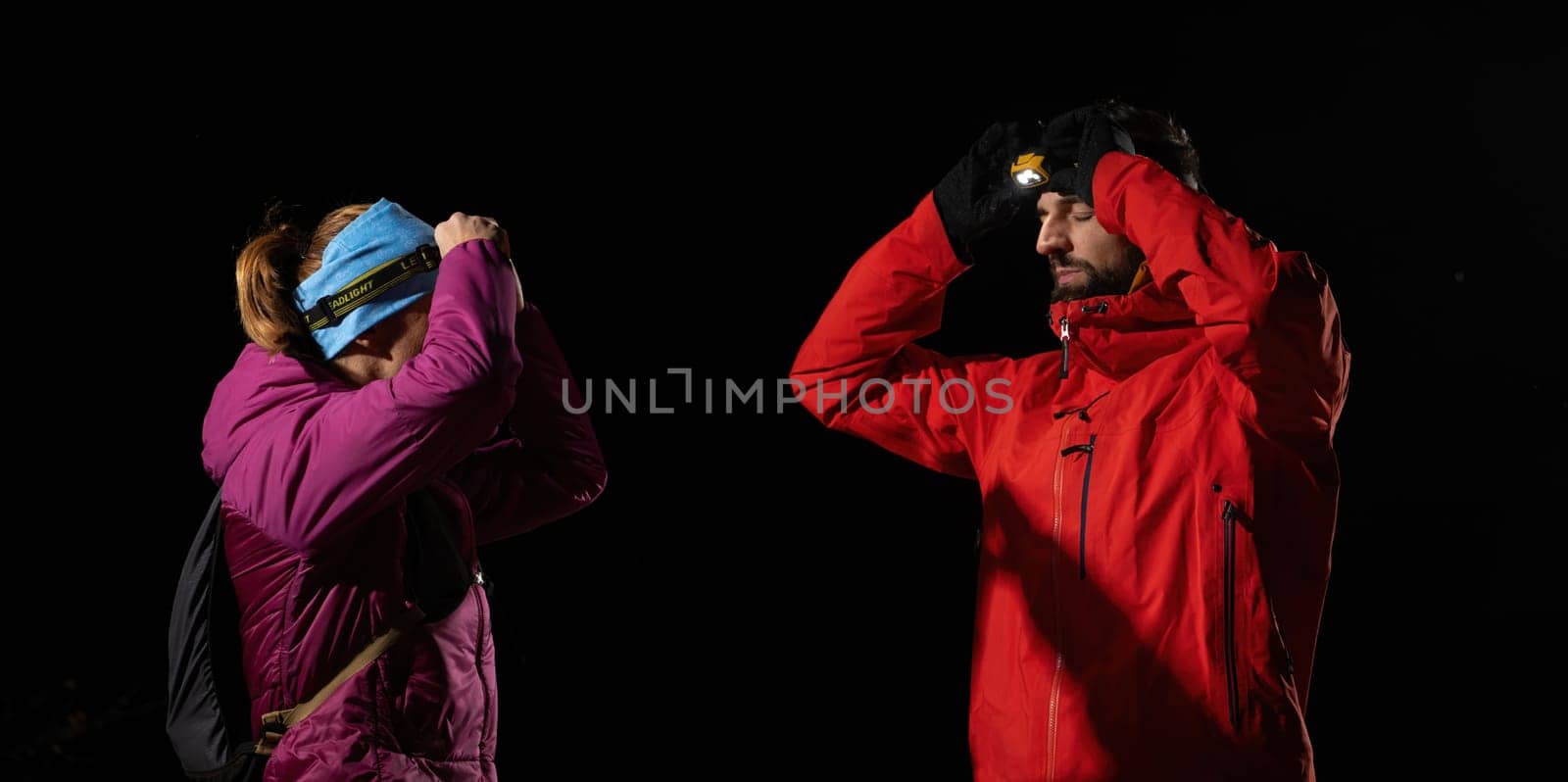 A woman provides headlamp-assisted first aid to a man outdoors in the dark, showcasing emergency preparedness in extreme conditions.
