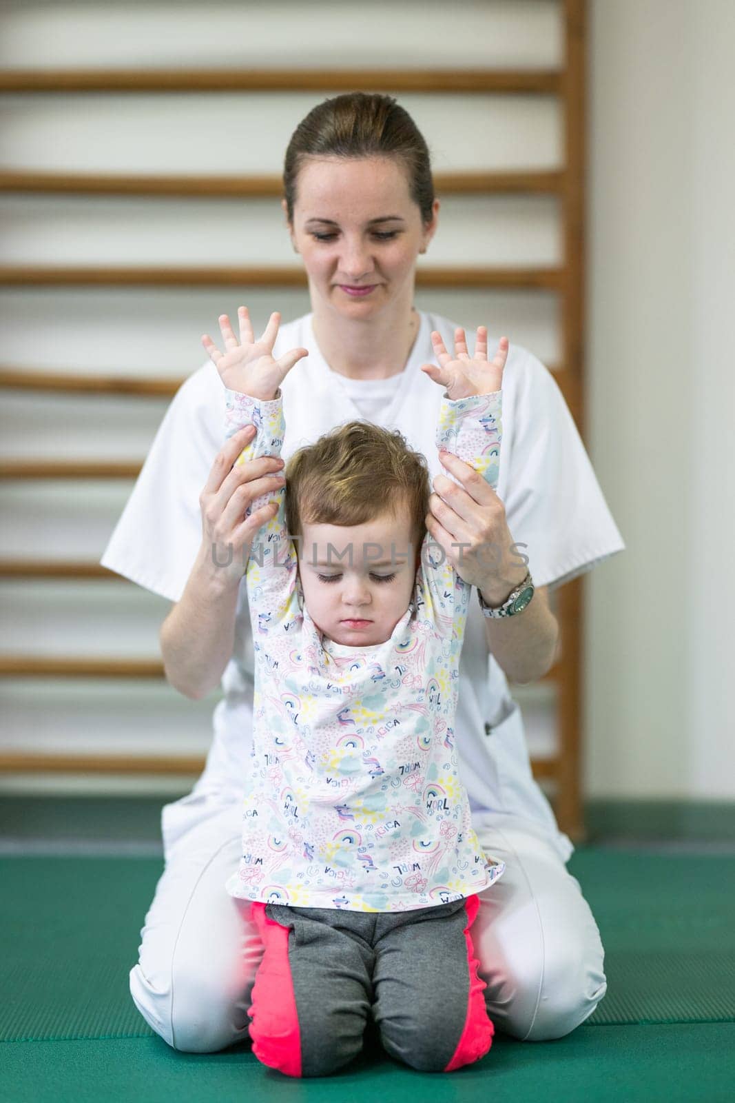 Female physiotherapist helping a young child with physical exercises in a rehabilitation center. Pediatric therapy and development concept.
