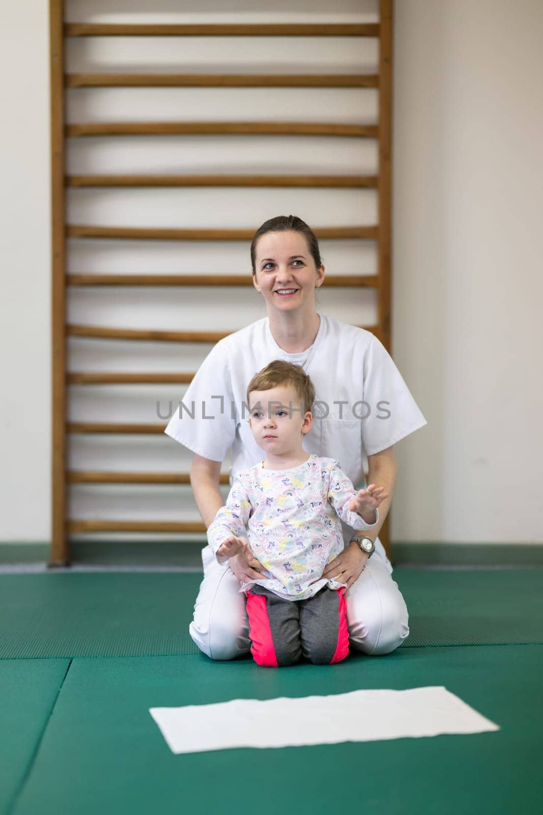 Female physiotherapist helping a young child with physical exercises in a rehabilitation center. Pediatric therapy and development concept.