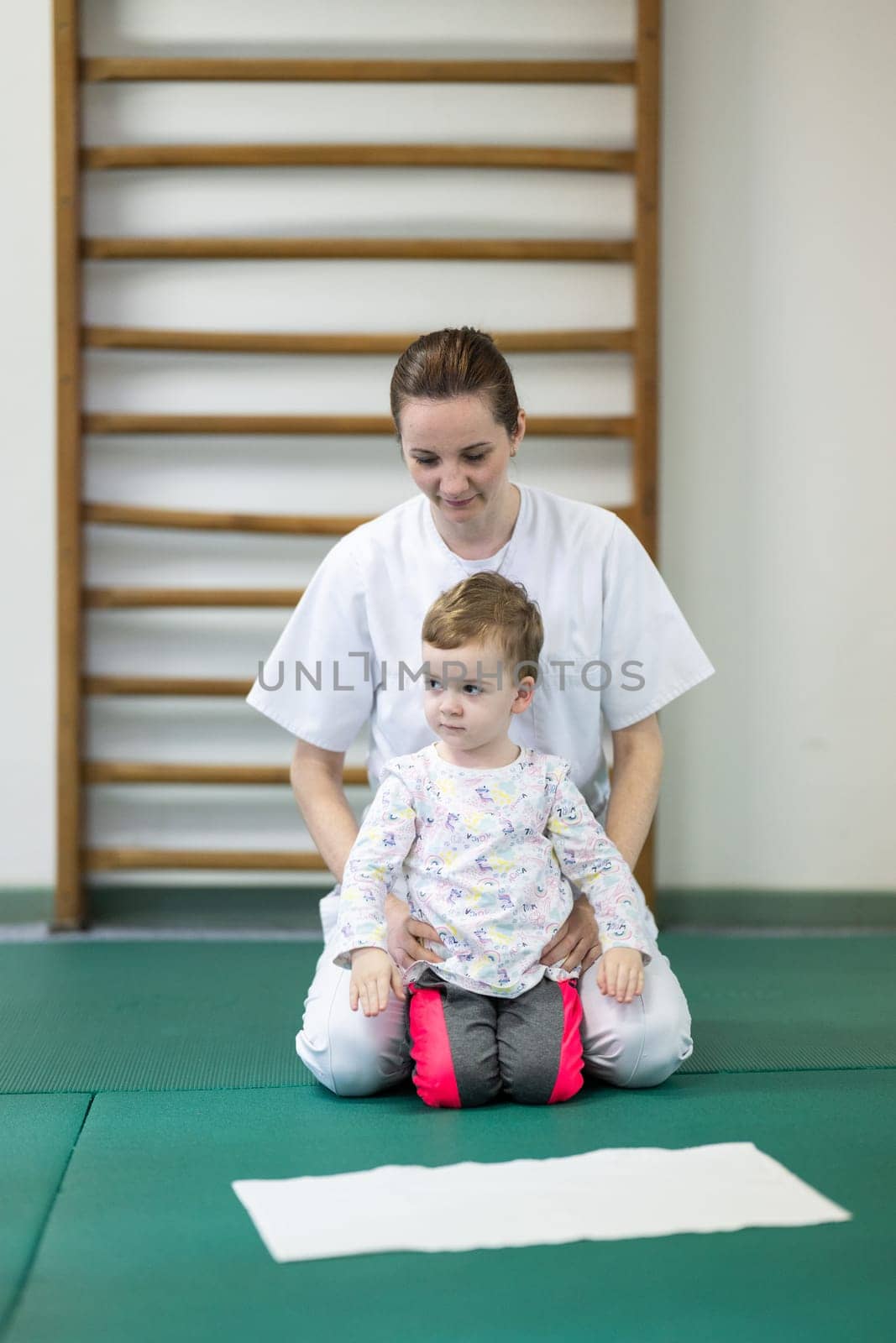 Female physiotherapist helping a young child with physical exercises in a rehabilitation center. Pediatric therapy and development concept.