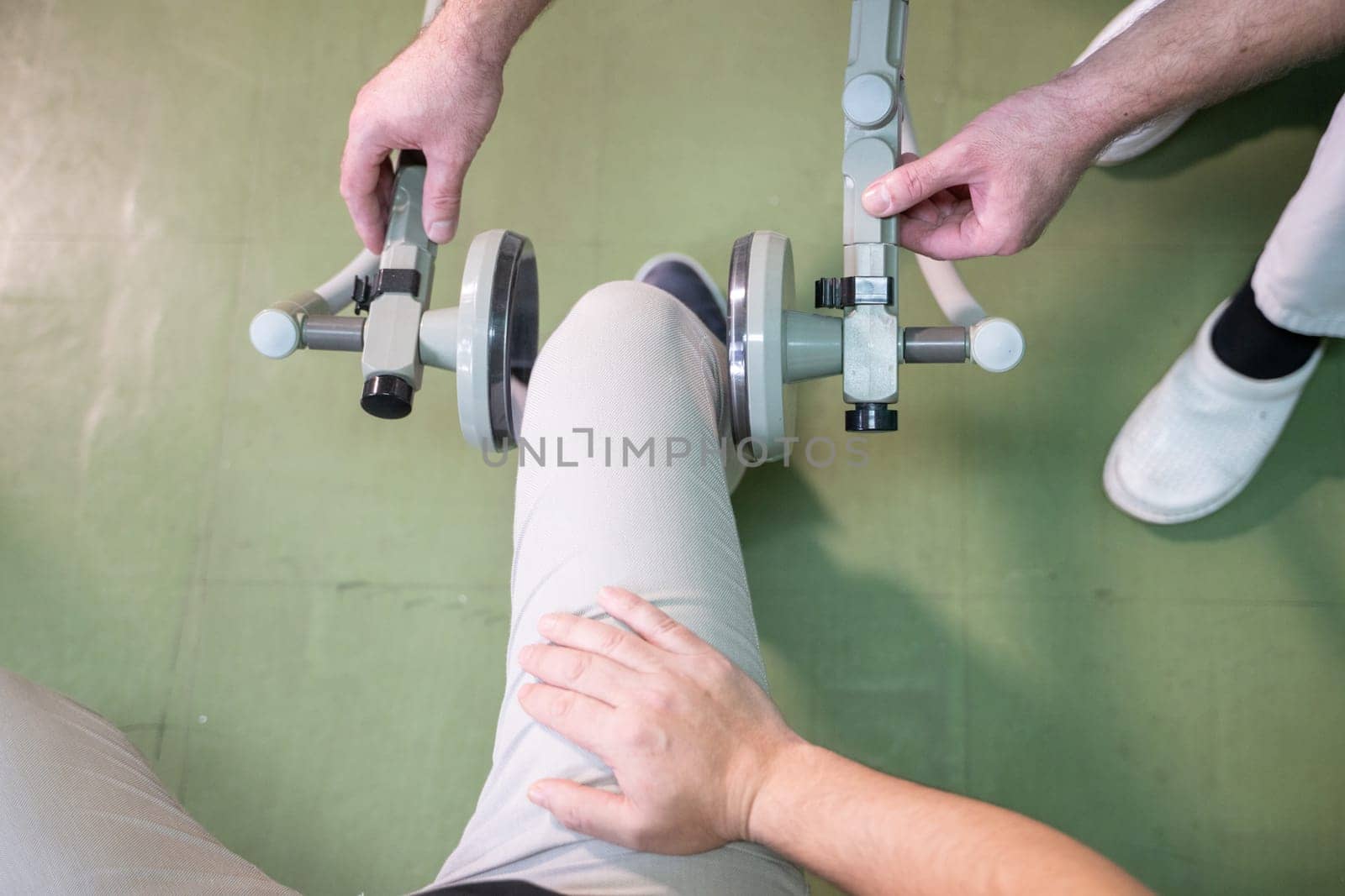 Top down view of a person using a rehabilitation machine for leg therapy, focusing on muscle training and mobility.