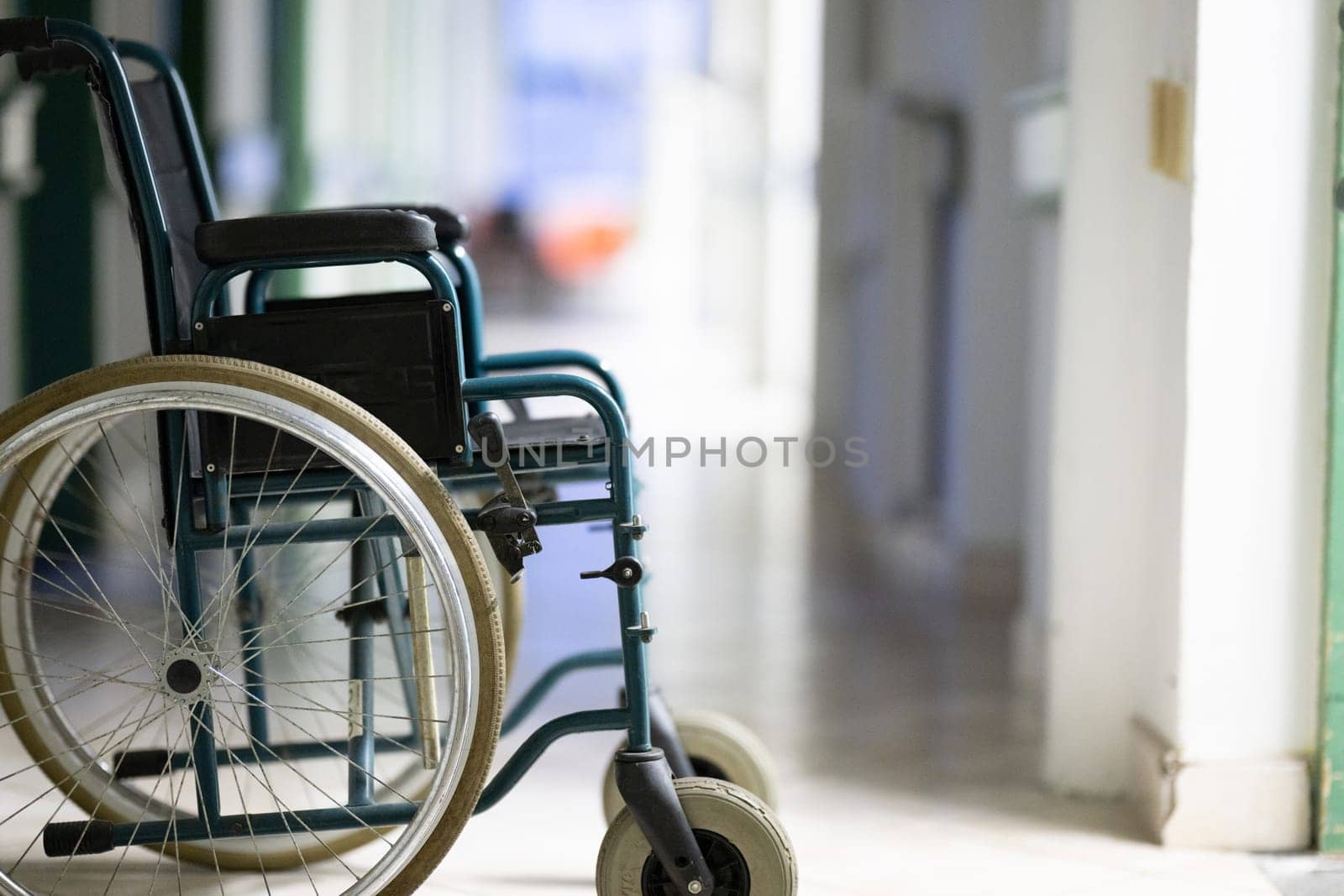 Unattended wheelchair positioned in a bright hospital corridor. Concept of accessibility and patient transport.