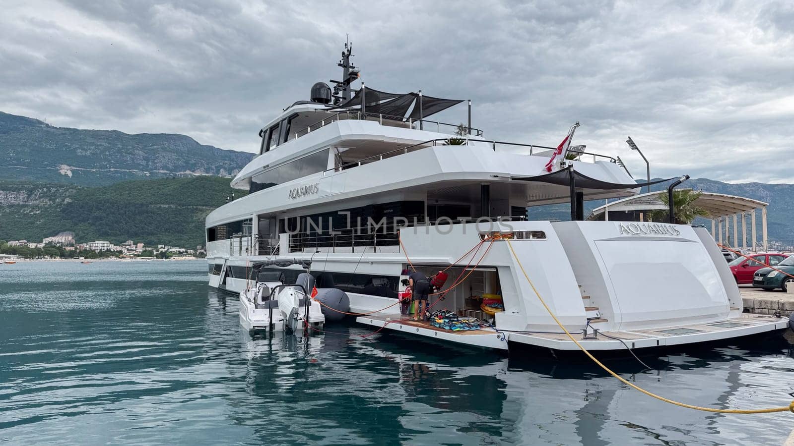 Budva, Montenegro - May 21, 2025: Elegant yacht Aquarius is anchored in calm waters with stunning mountain scenery