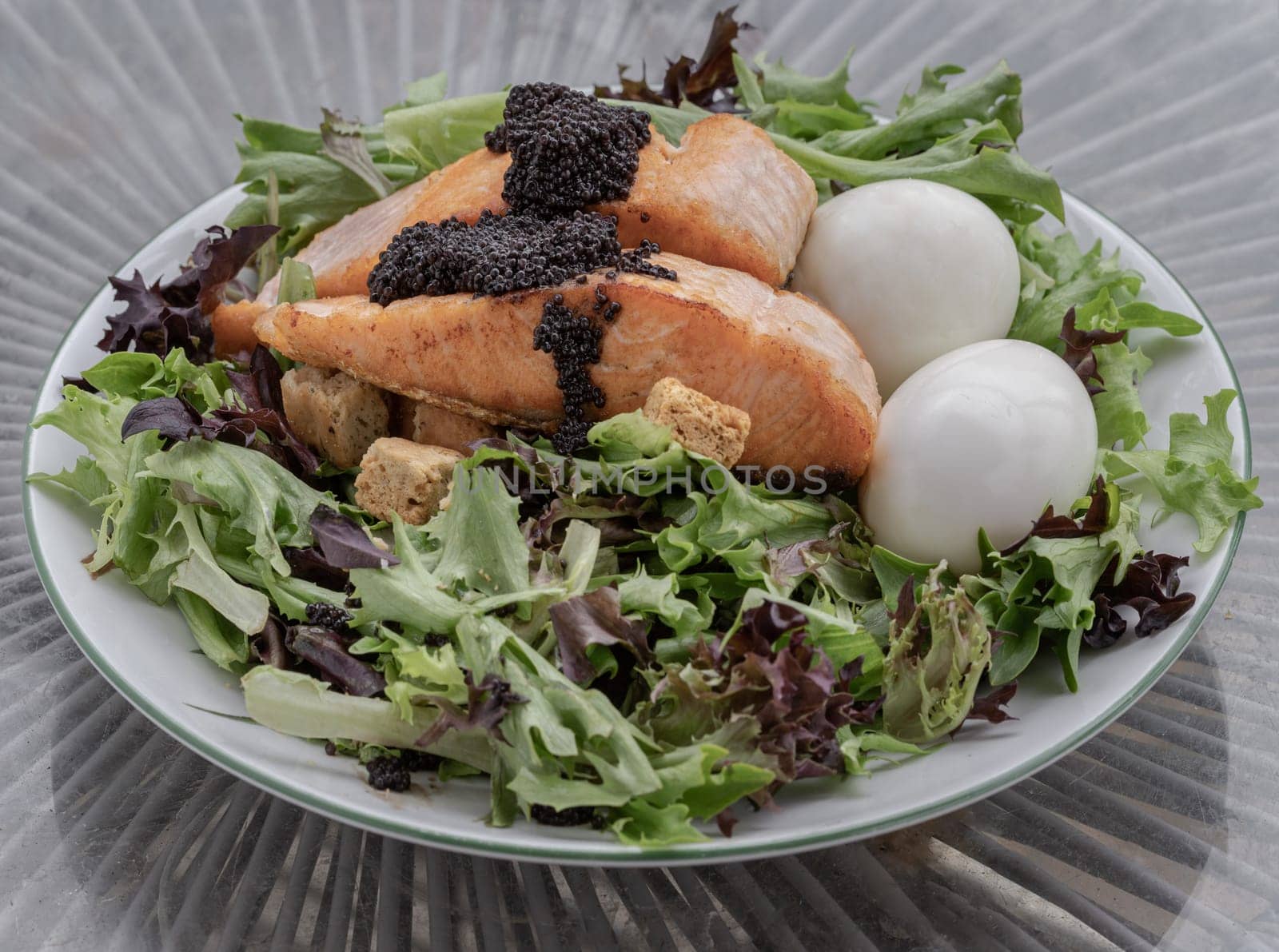 Homemade salad with Grilled salmon fillets, Boiled egg and Croutons topping Caviar on plate. Simple yet very tasty dish, use it as your Wallpaper, Poster and Space for text, Selective focus.