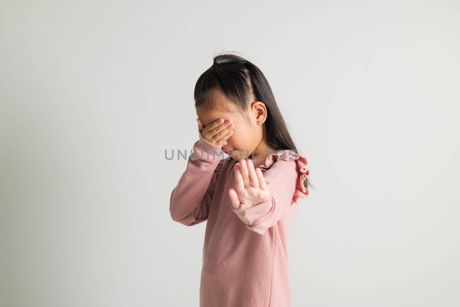 Stop hand of kindergarten child. Asian little kid girl doing stop sing gesture with palm of the hand at studio shot isolated on white background, child raised hand five fingers