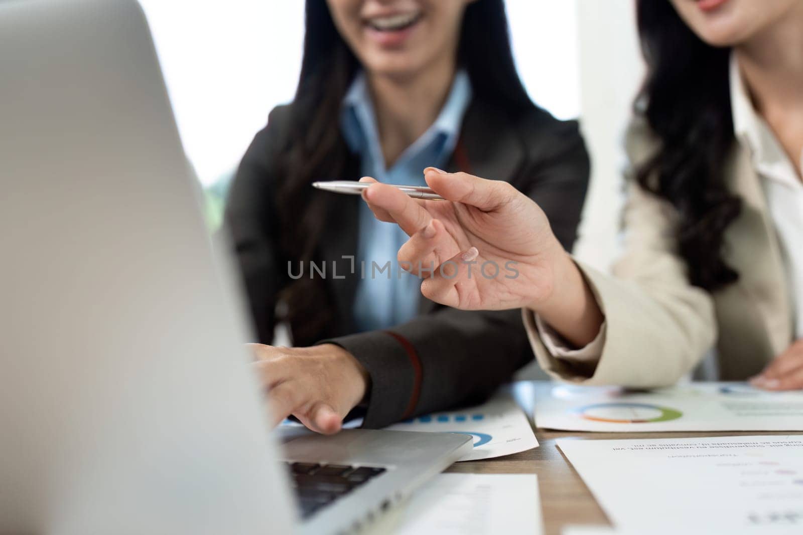 Two professionals engage in a collaborative discussion while reviewing data on a laptop, showcasing teamwork in a modern office.