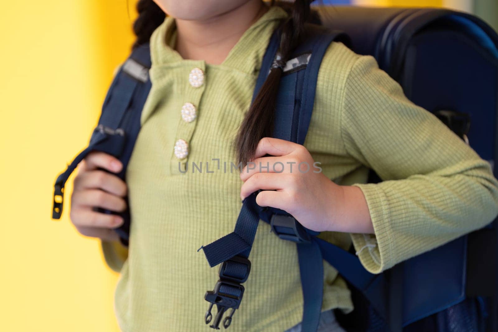 A young student prepares for school by adjusting their backpack, ready for a day of learning and adventure.