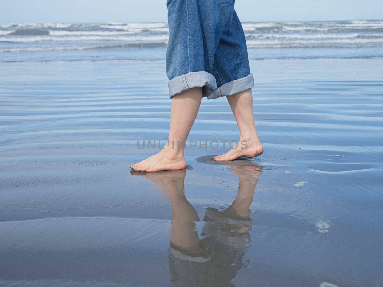 A closeup conceptual photos of a woman's feet shown barefooted walking on the beach by the pacific ocean in Washington.