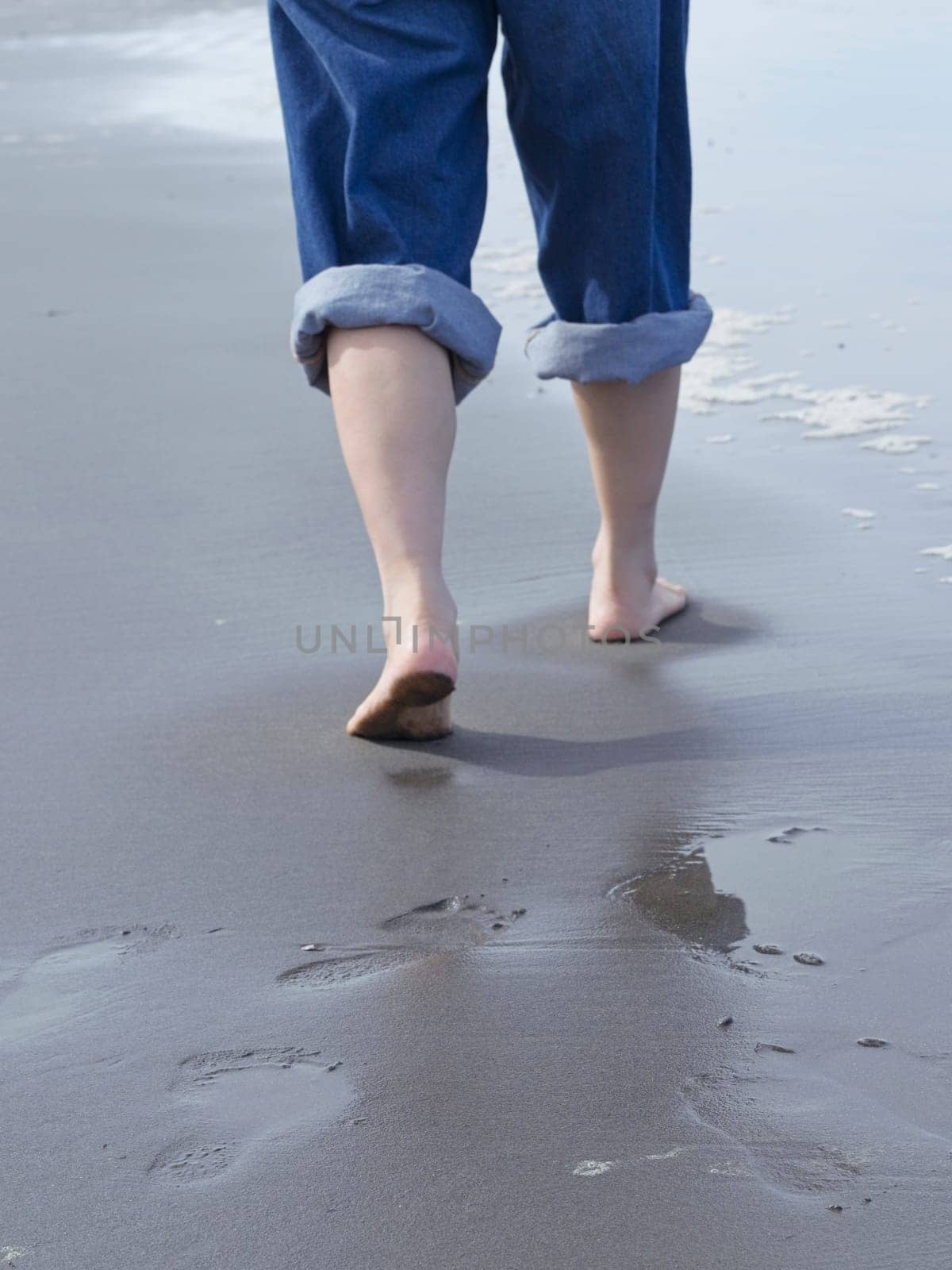 A closeup conceptual photos of a woman's feet shown barefooted walking on the beach by the pacific ocean in Washington.