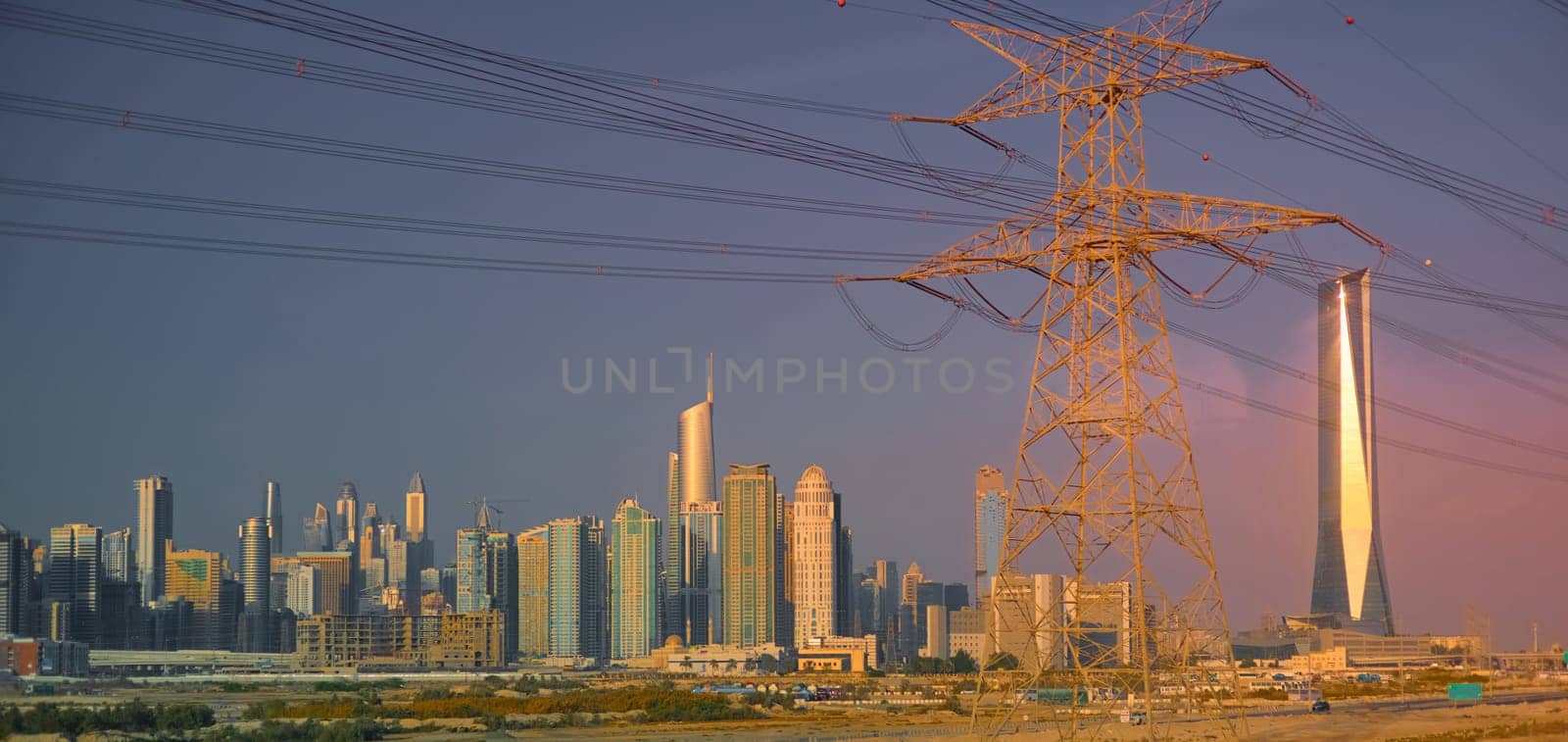 Dubai's high-voltage power lines at sunset, skyscrapers in the haze in the background. High quality photo