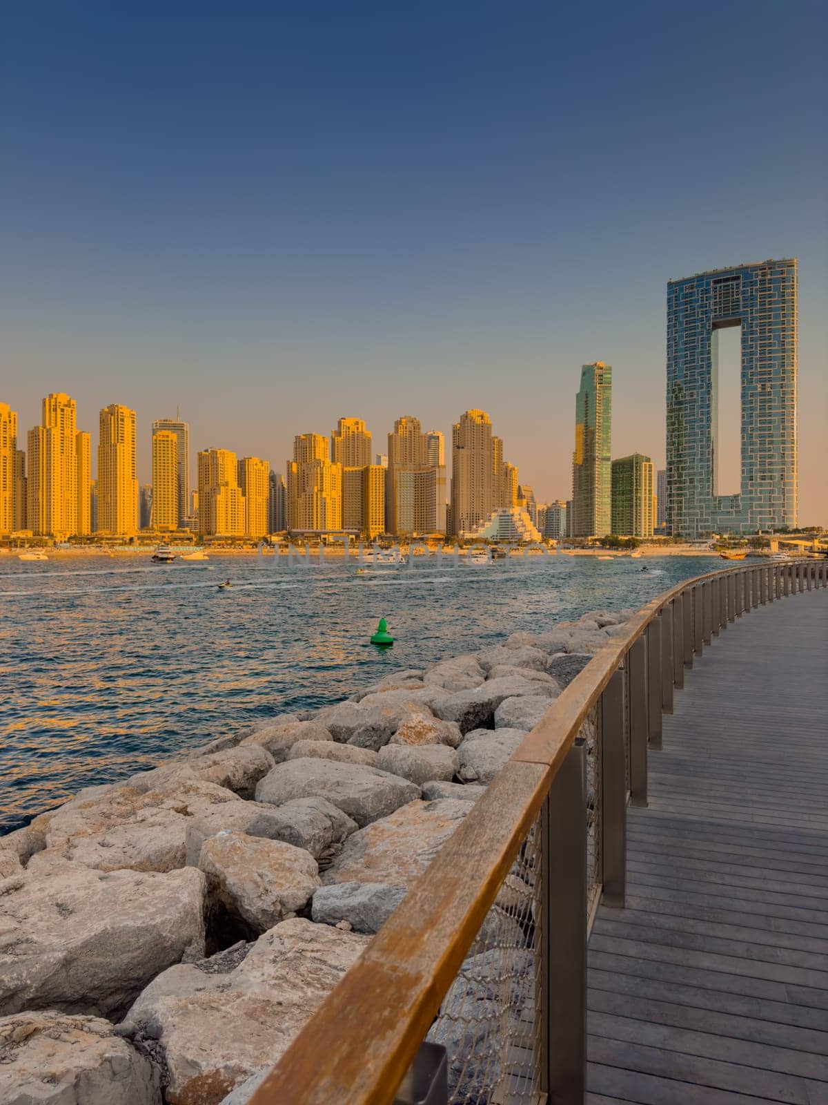 UAE, Dubai, 21 September 2024: Lively navigation of Dubai Marina along the waterfront against the backdrop of the beach and skyscrapers at sunset, boats and yachts with people on board. High quality photo