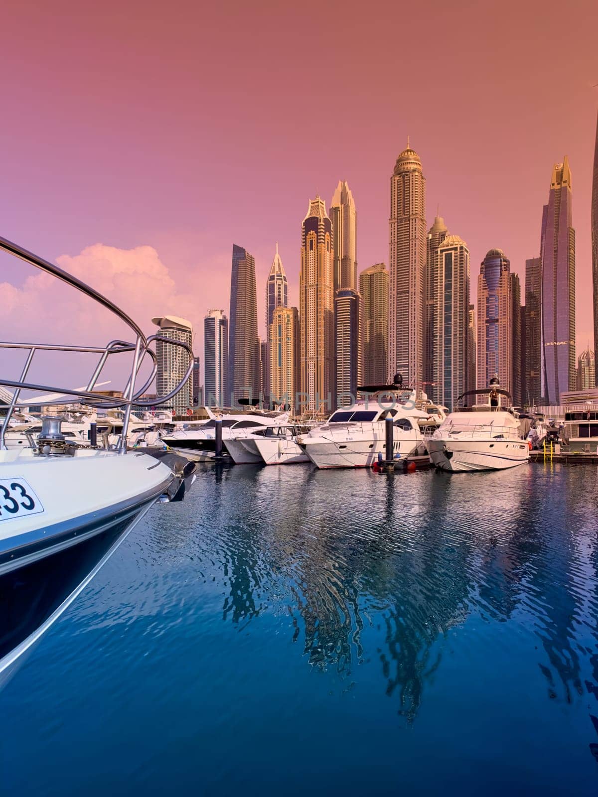 UAE, Dubai, 29 September 2024: Skyscrapers from Dubai harbor marina at sunny day, luxury yachts and boats are moored in port. High quality photo