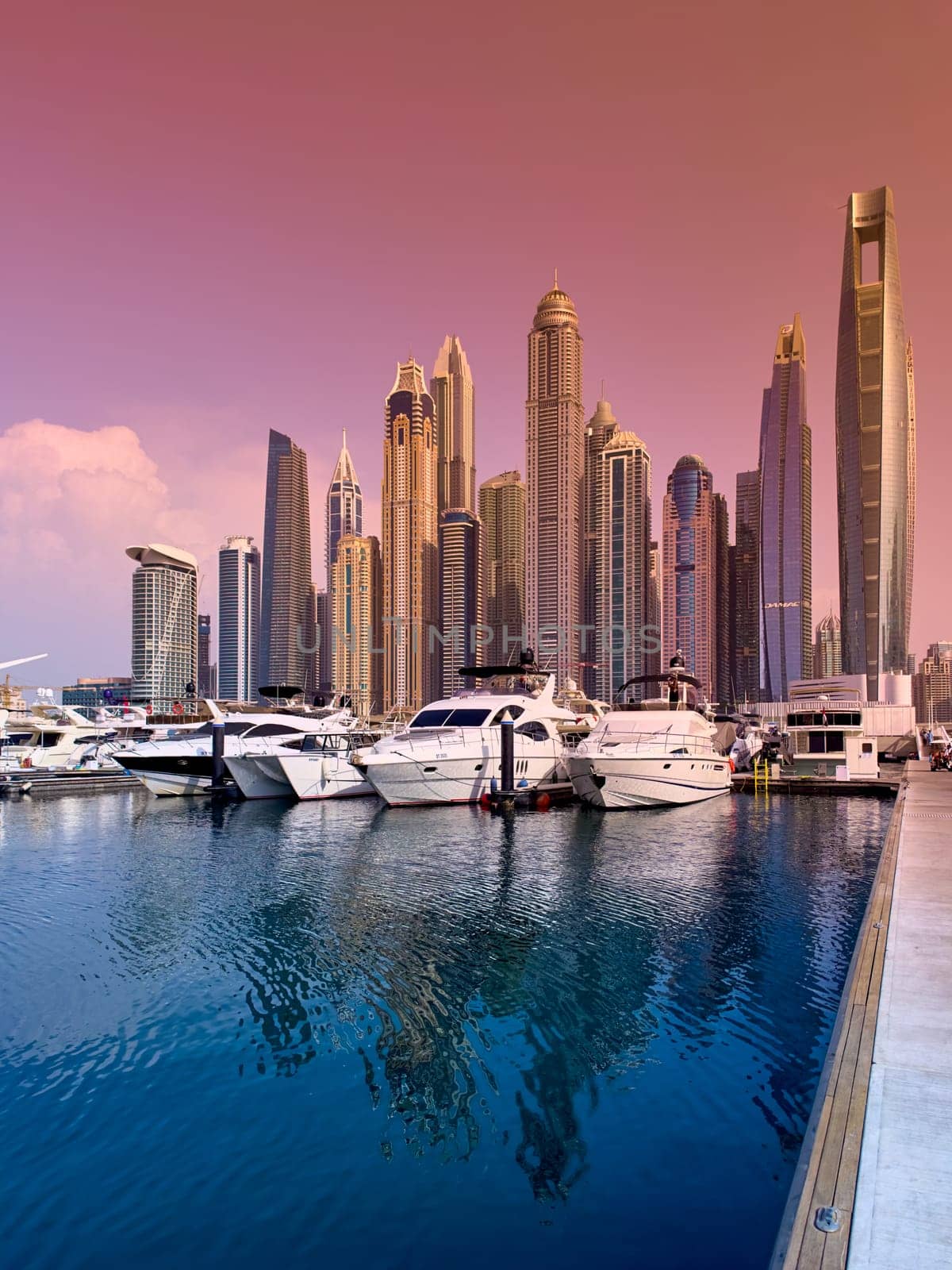 UAE, Dubai, 29 September 2024: Skyscrapers from Dubai harbor marina at sunny day, luxury yachts and boats are moored in port. High quality photo