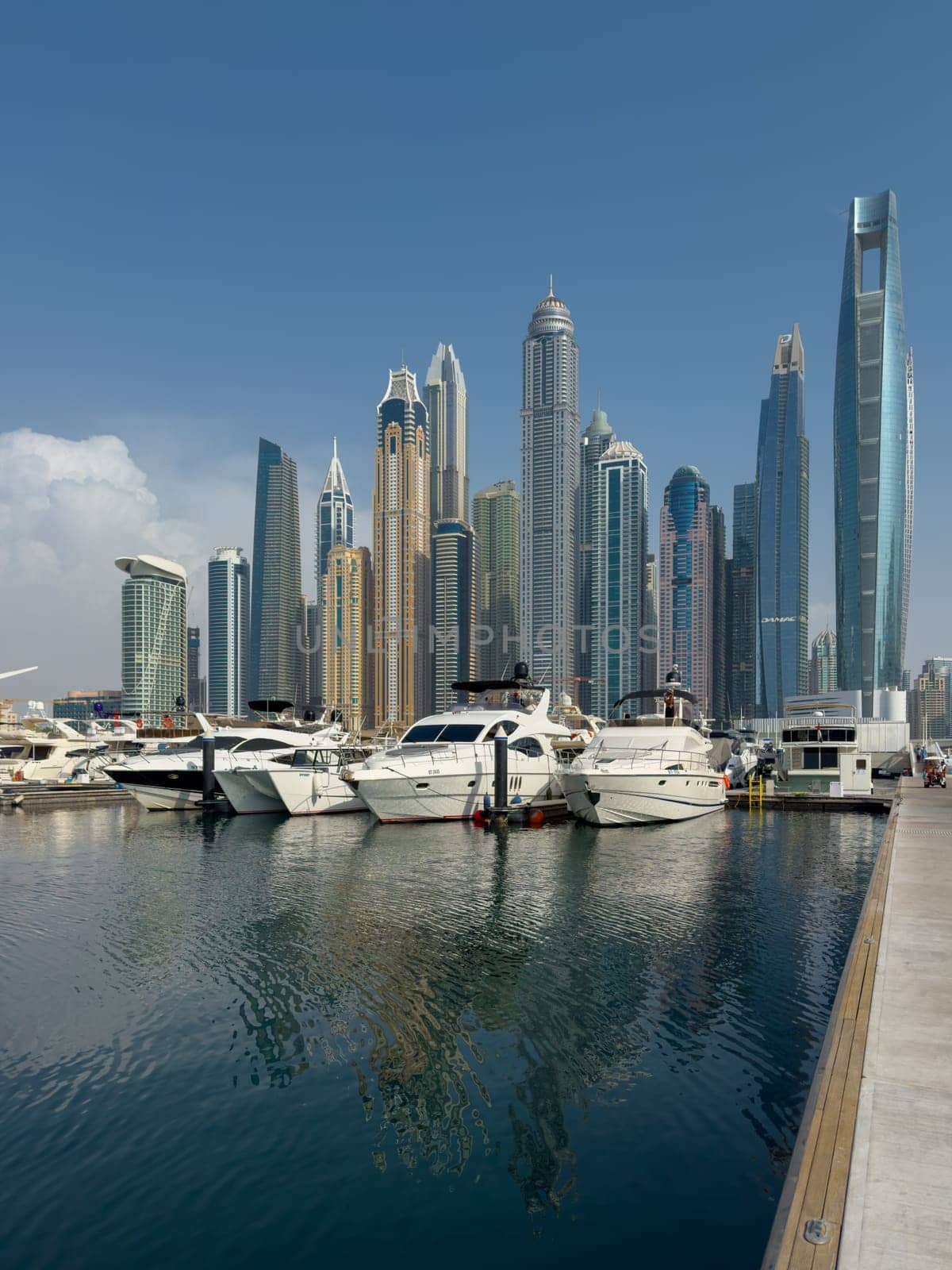 UAE, Dubai, 29 September 2024: Skyscrapers from Dubai harbor marina at sunny day, luxury yachts and boats are moored in port. High quality photo