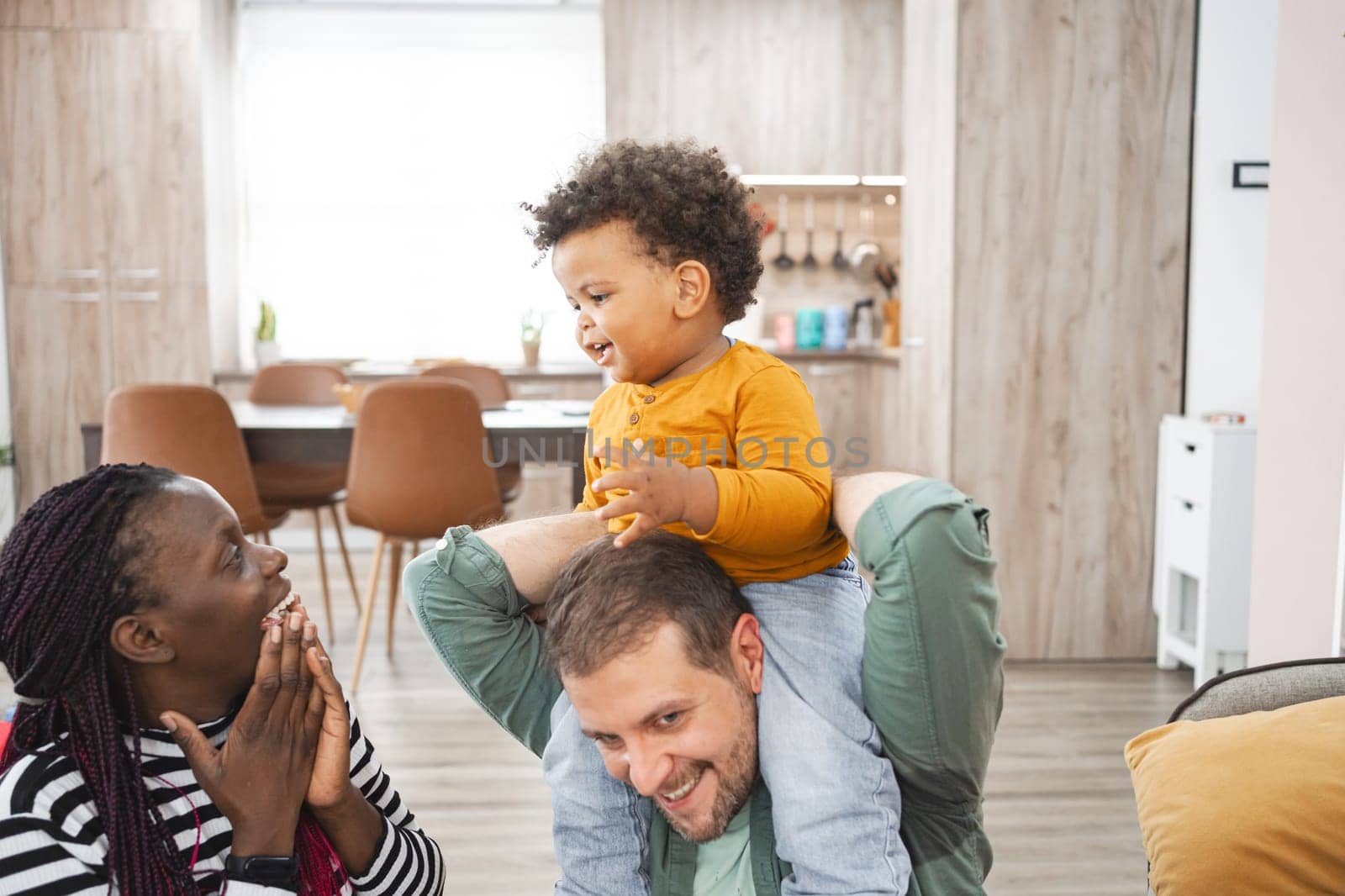 A joyful child siting on a parent s shoulders while family bonds.