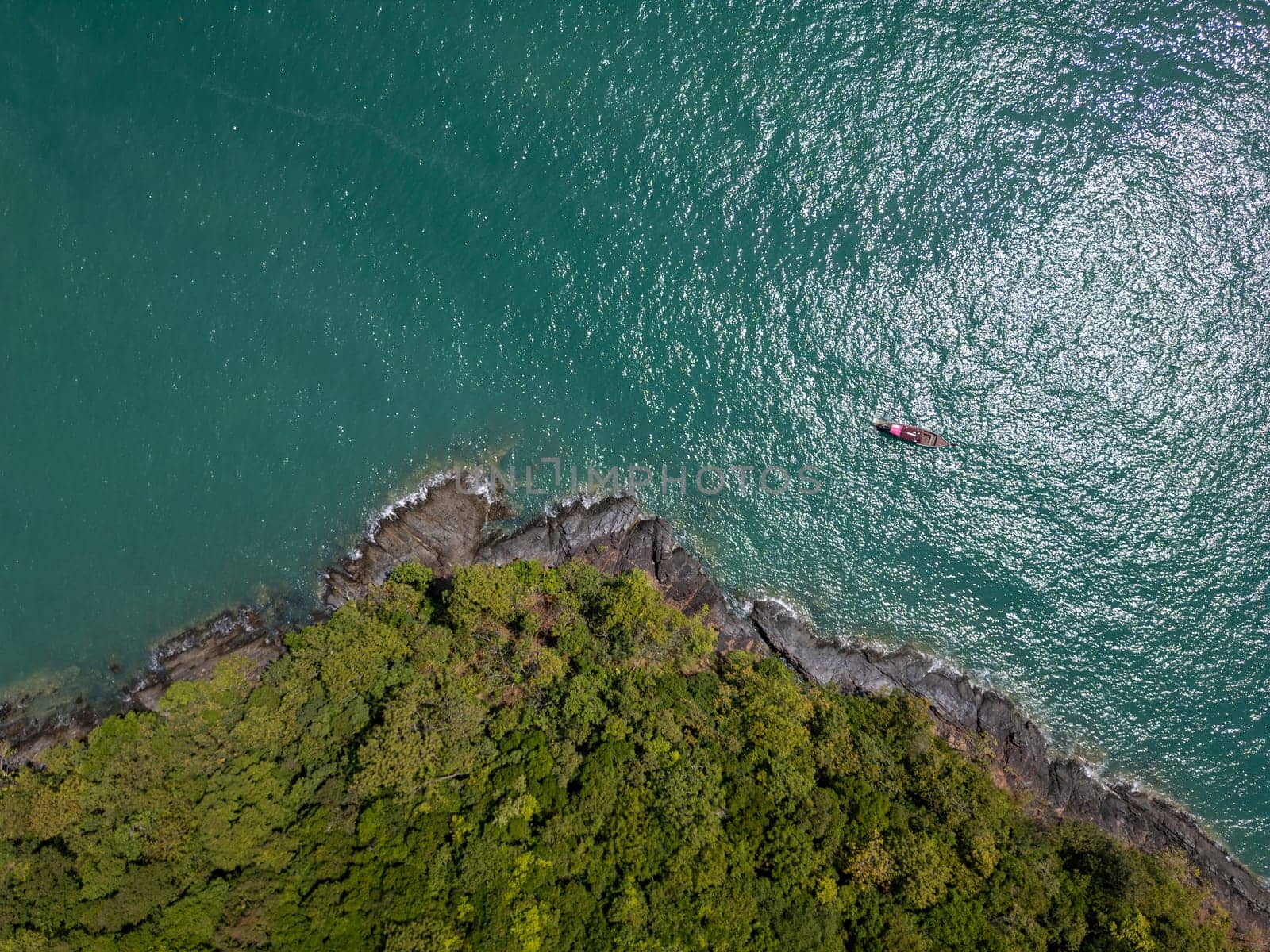 Aerial view of boat anchored on a peaceful shore in Thailand blue waters, showcasing motorboats and sailboats docked near a sandy shore, surrounded by lush palm trees and a beautiful summer sky.
