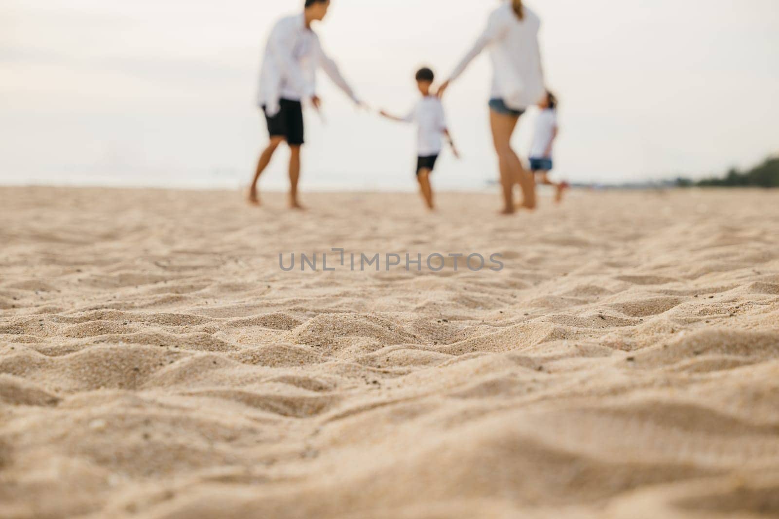 Smiling father and mother with son and daughter having fun on the beach. Running playing and laughing creating cheerful moments of family bonding and joy during summer. Family on beach vacation