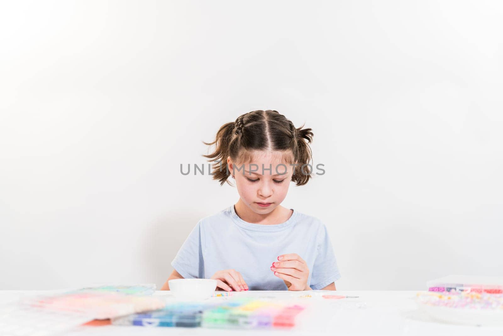 Little girl enjoys crafting colorful bracelets with vibrant clay beads set.