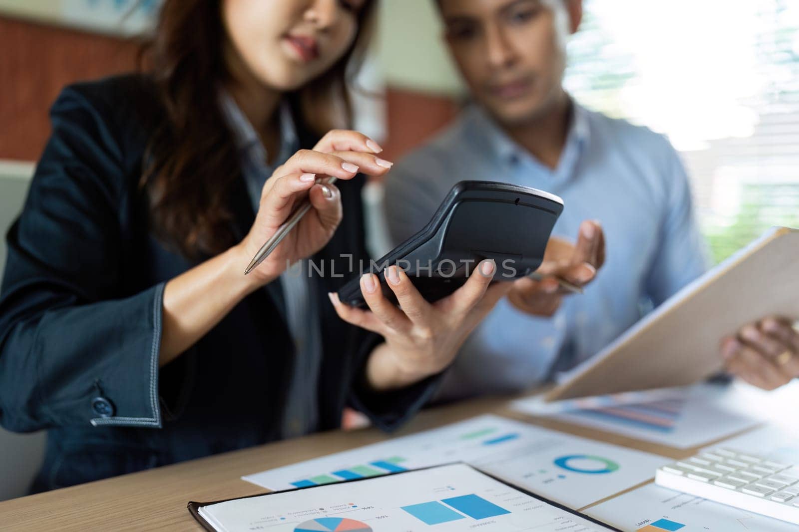 Two business partners reviewing financial calculations and discussing plans in a collaborative office setting.