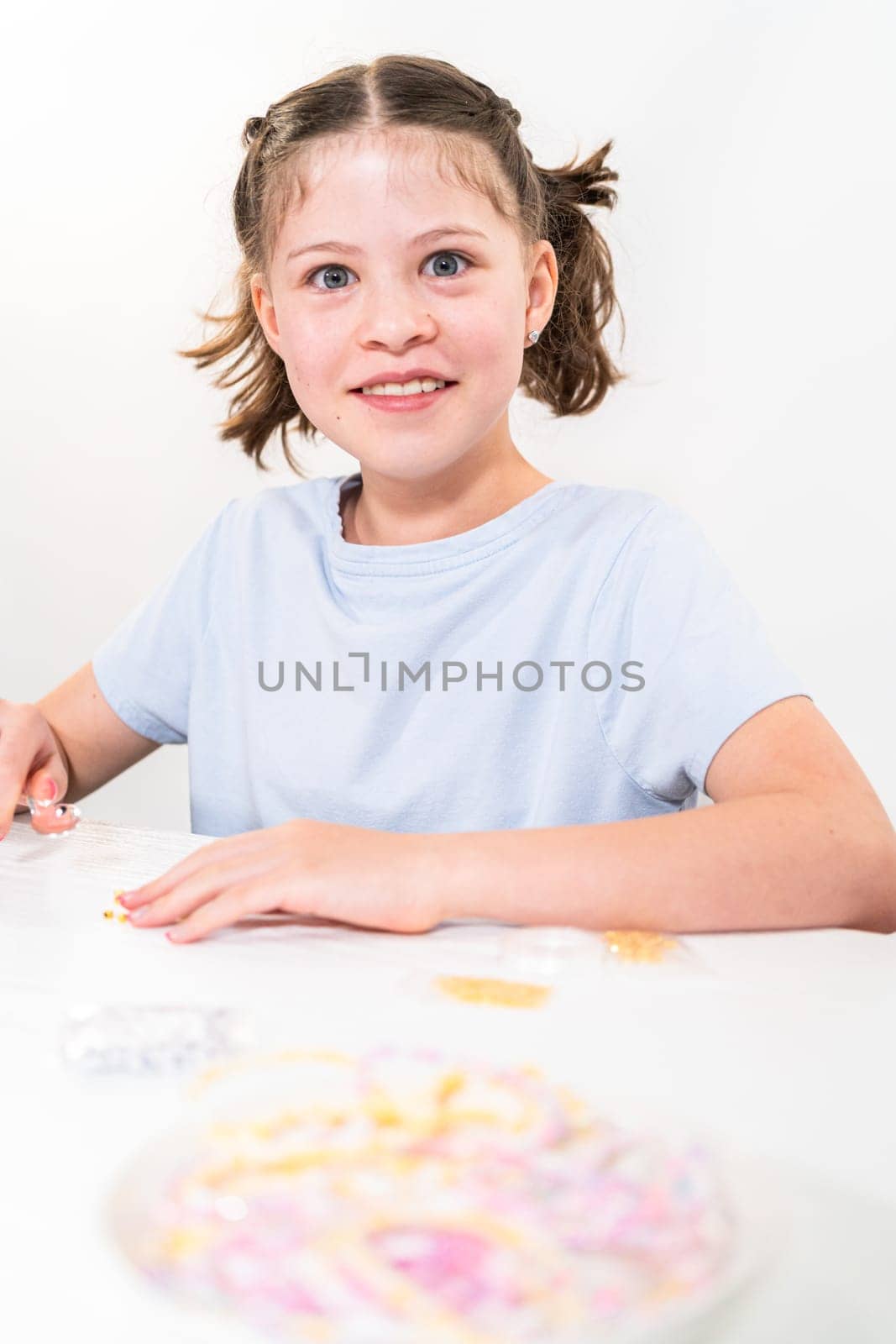 Little girl enjoys crafting colorful bracelets with vibrant clay beads set.