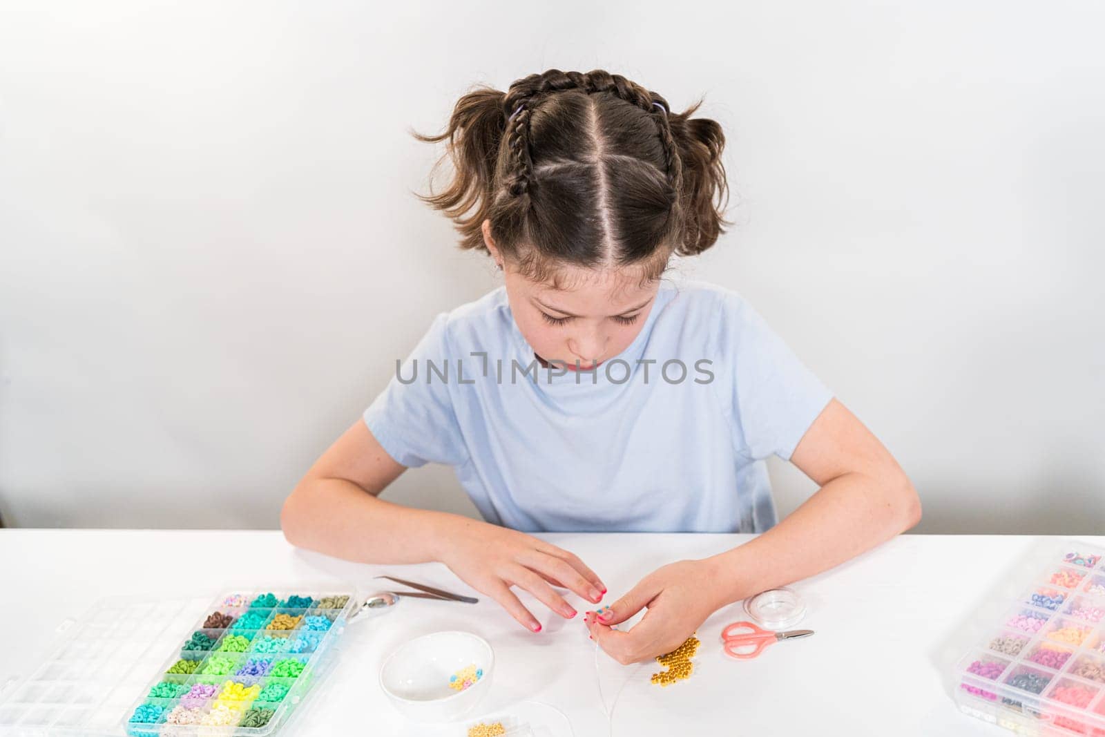 Little girl enjoys crafting colorful bracelets with vibrant clay beads set.