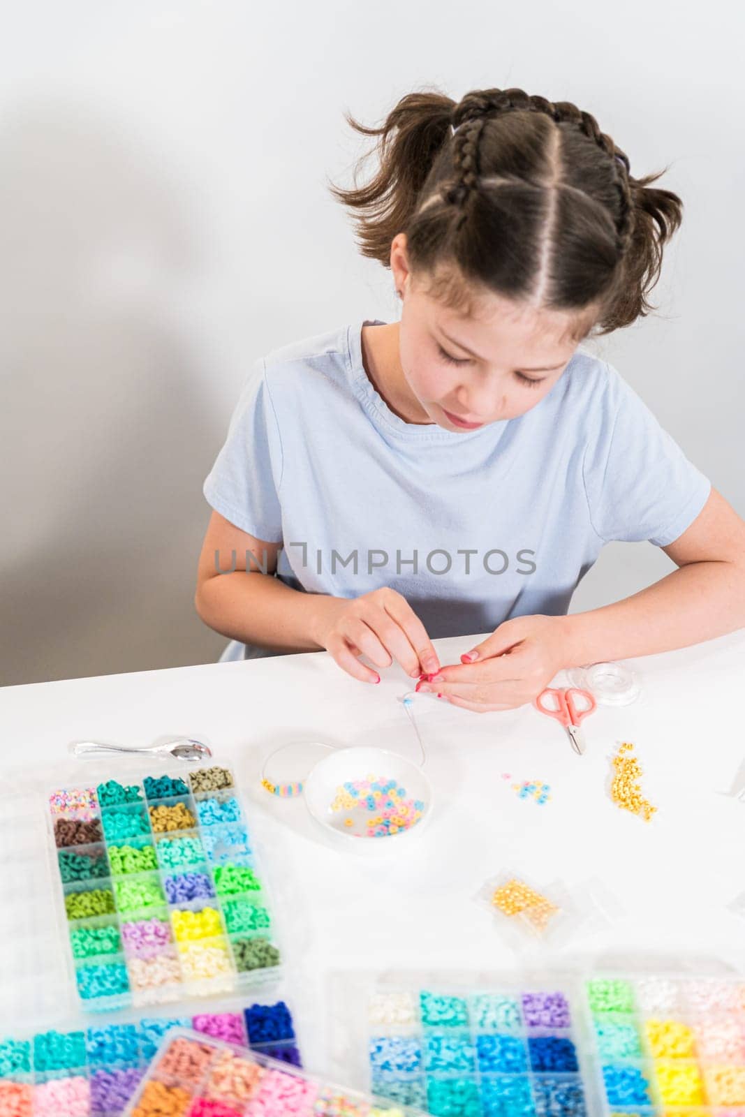Little girl enjoys crafting colorful bracelets with vibrant clay beads set.