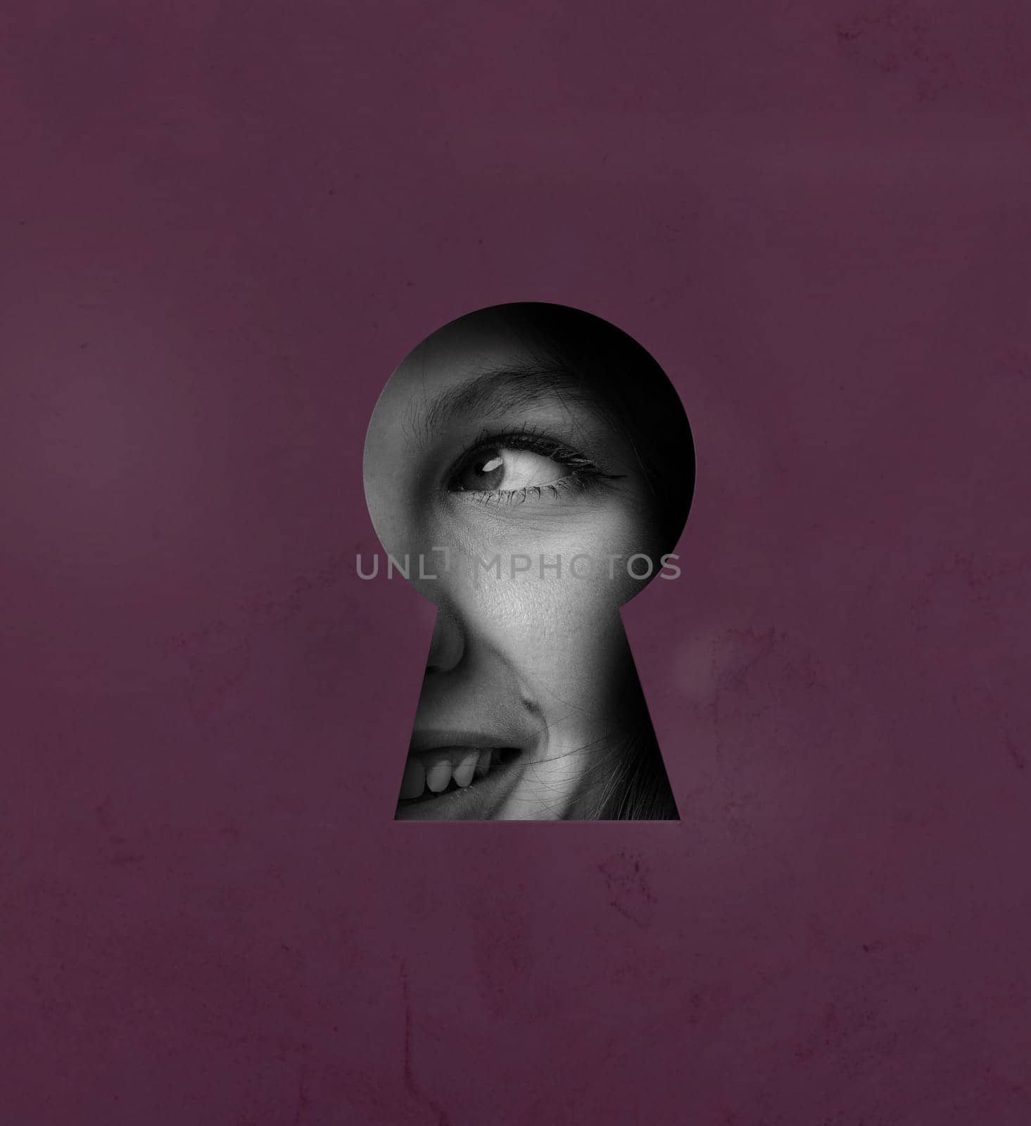 A keyhole offers a glimpse of a smiling face, capturing a moment of curiosity. The playful expression is accentuated by the unique framing and color of the background.